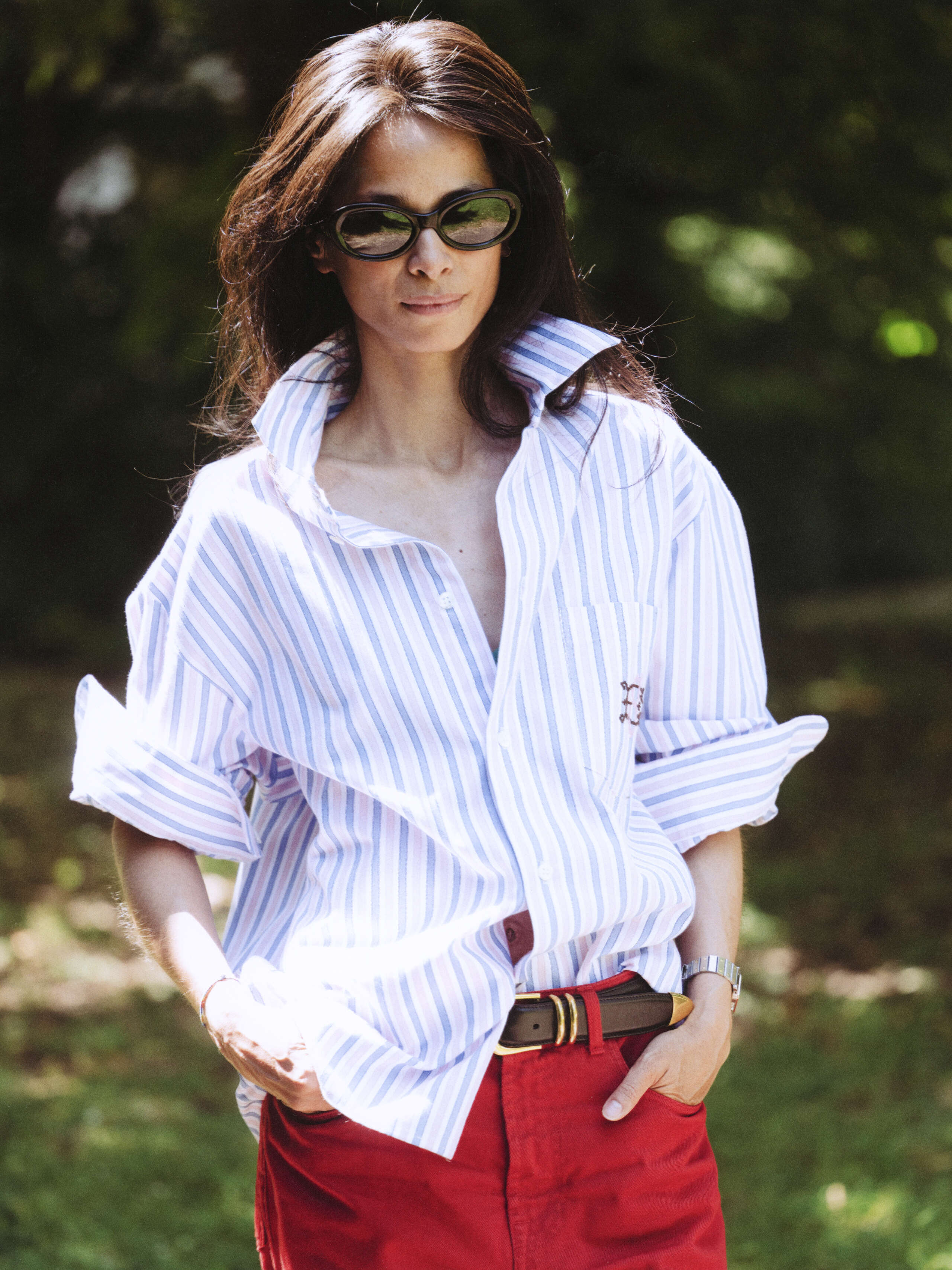 Picture of a women wearing a blouse featuring light blue and pink stripes and sunglasses
