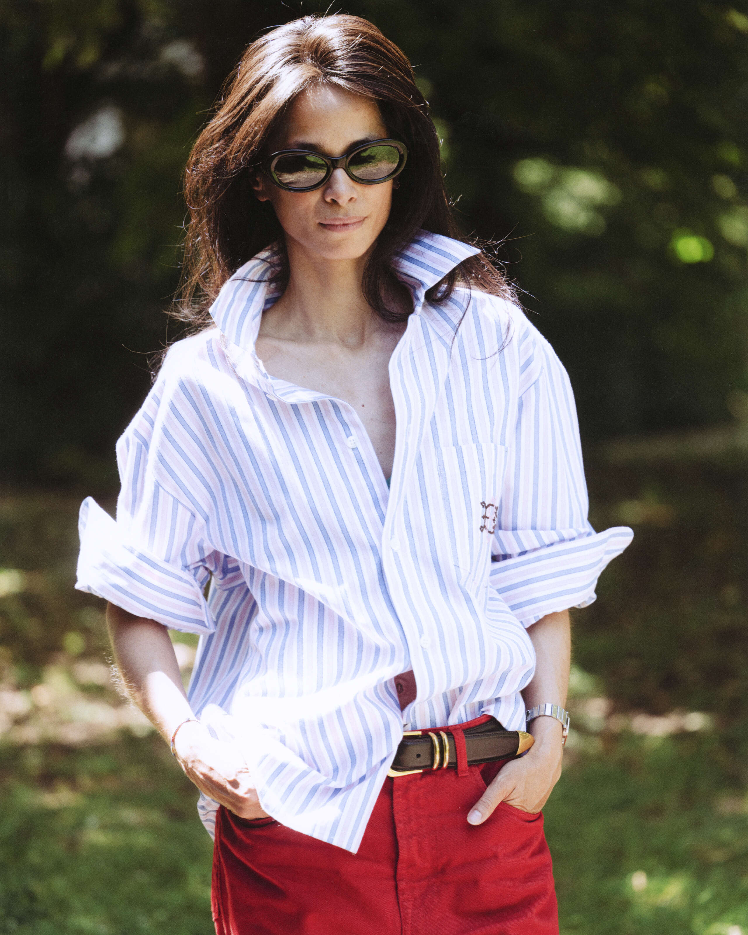 Picture of a women wearing a blouse featuring light blue and pink stripes and sunglasses
