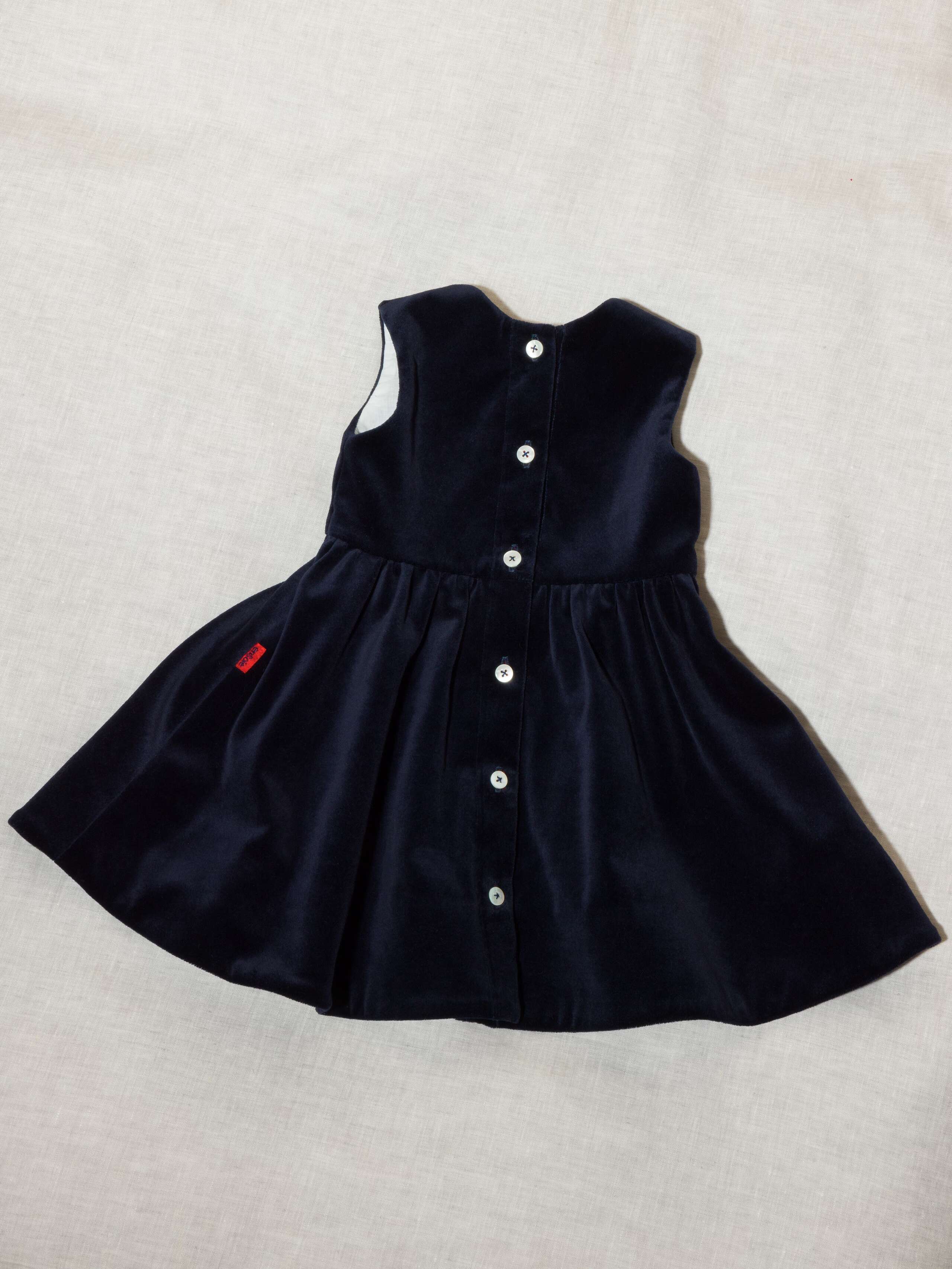 Detail of beautiful cotton velvet baby dress sleeveless with red silk bow handmade in Zurich, navy cotton velvet