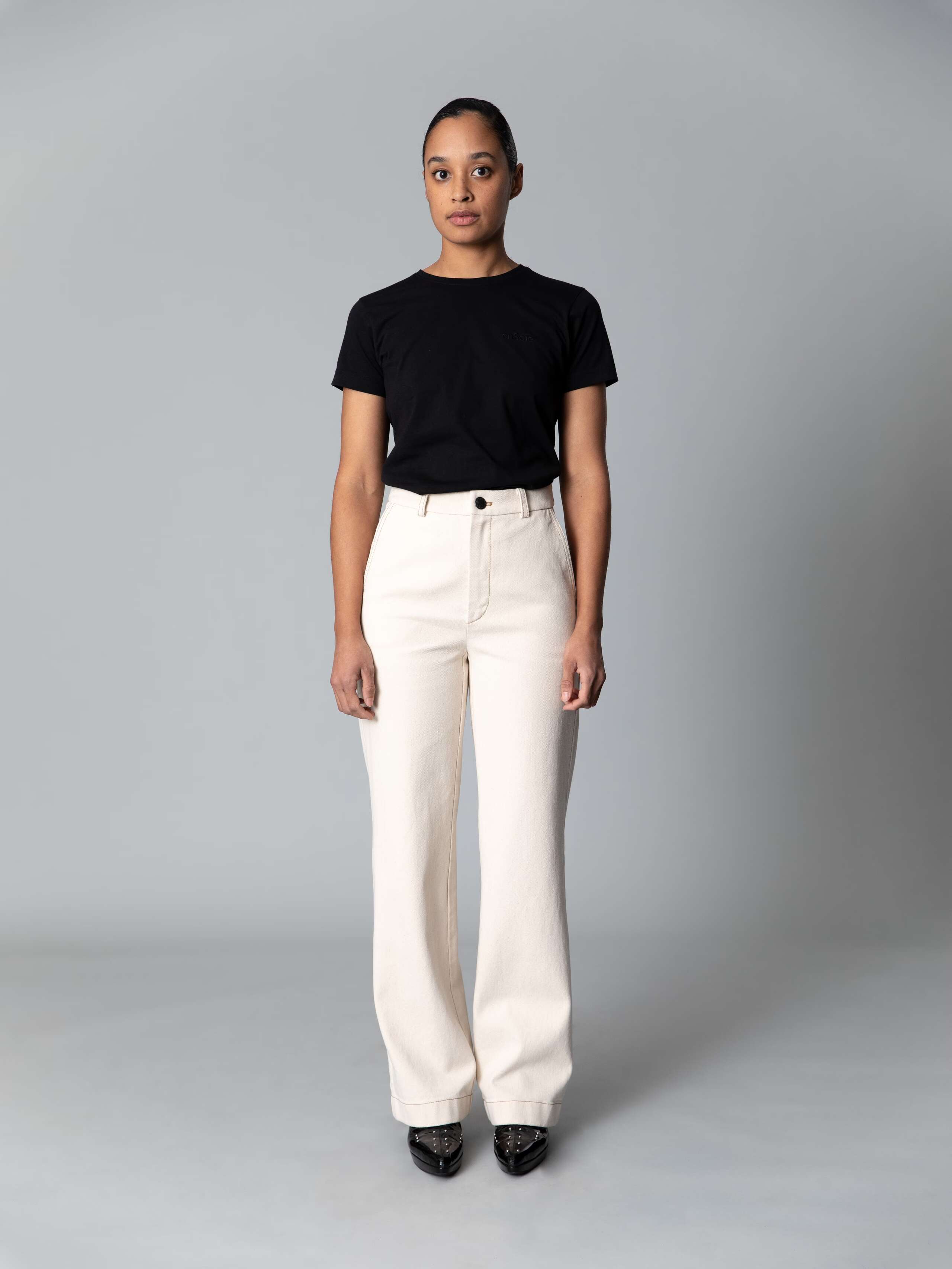 Model is weraing a cotton denim jeans in an ecru colour shade combined with a white shirt and black ballerina flats 