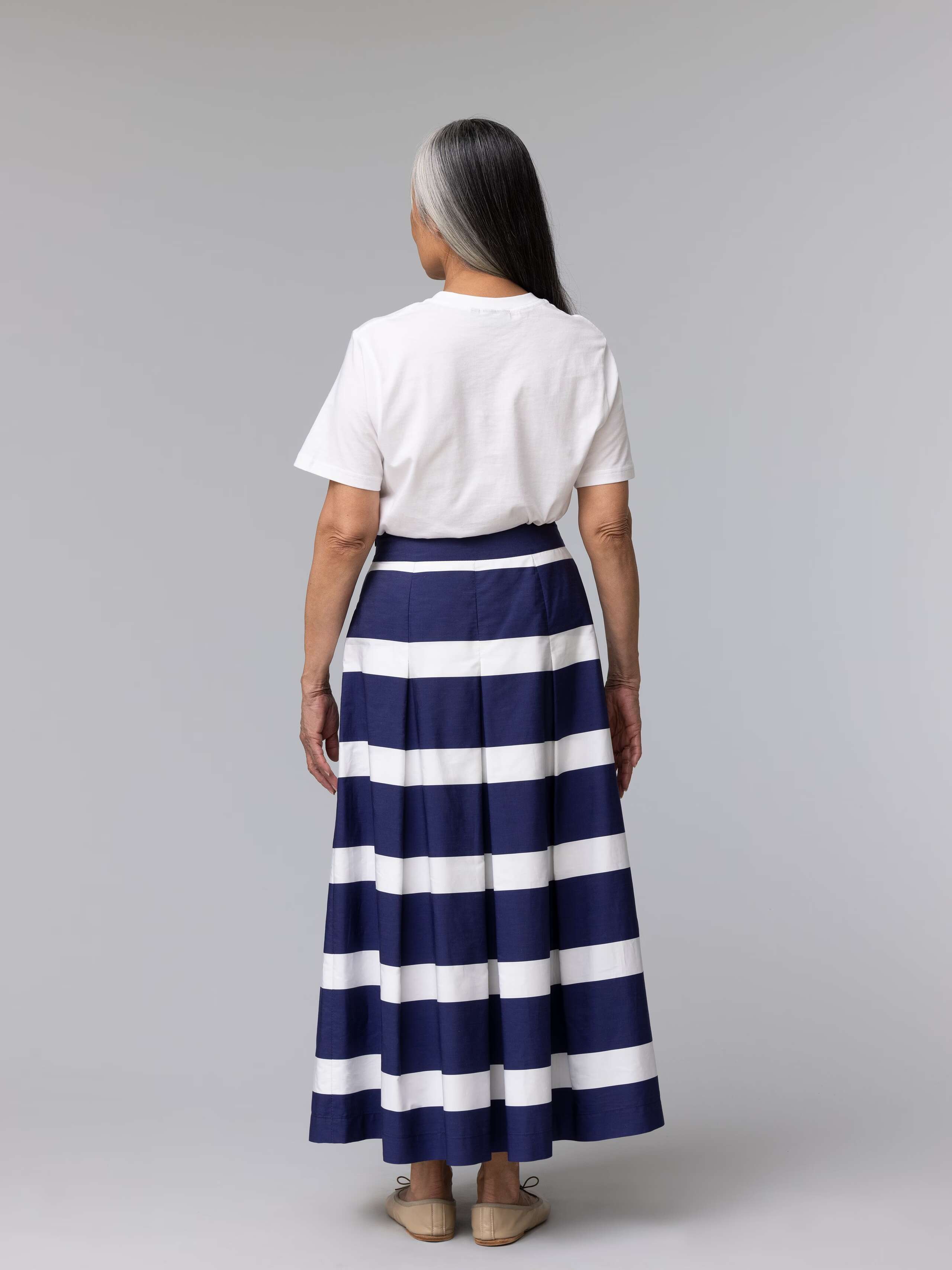 Beautiful elderly model is wearing a navy and white striped long cotton skirt