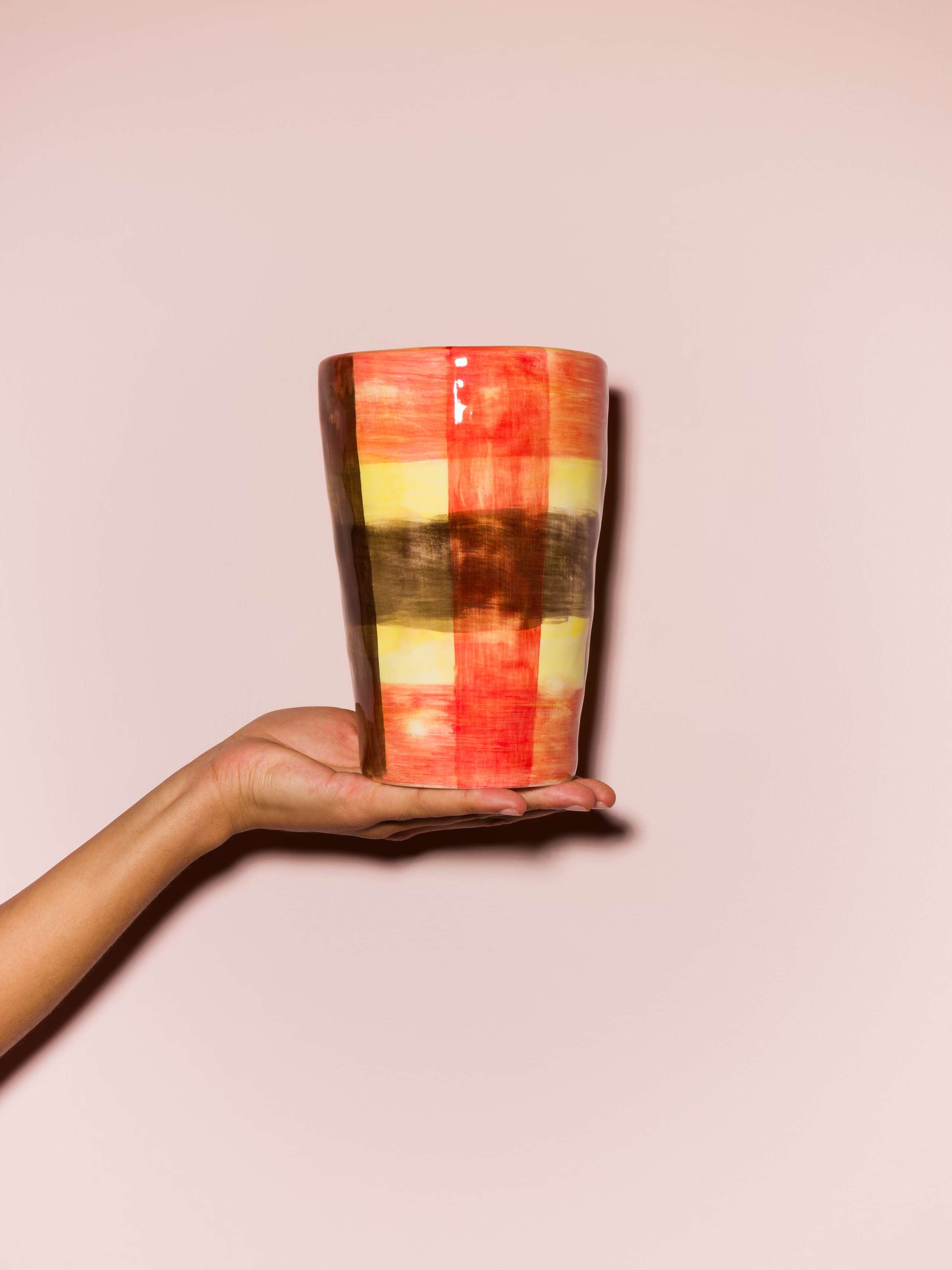 Picture of a hand holding a colourful hand printed vase