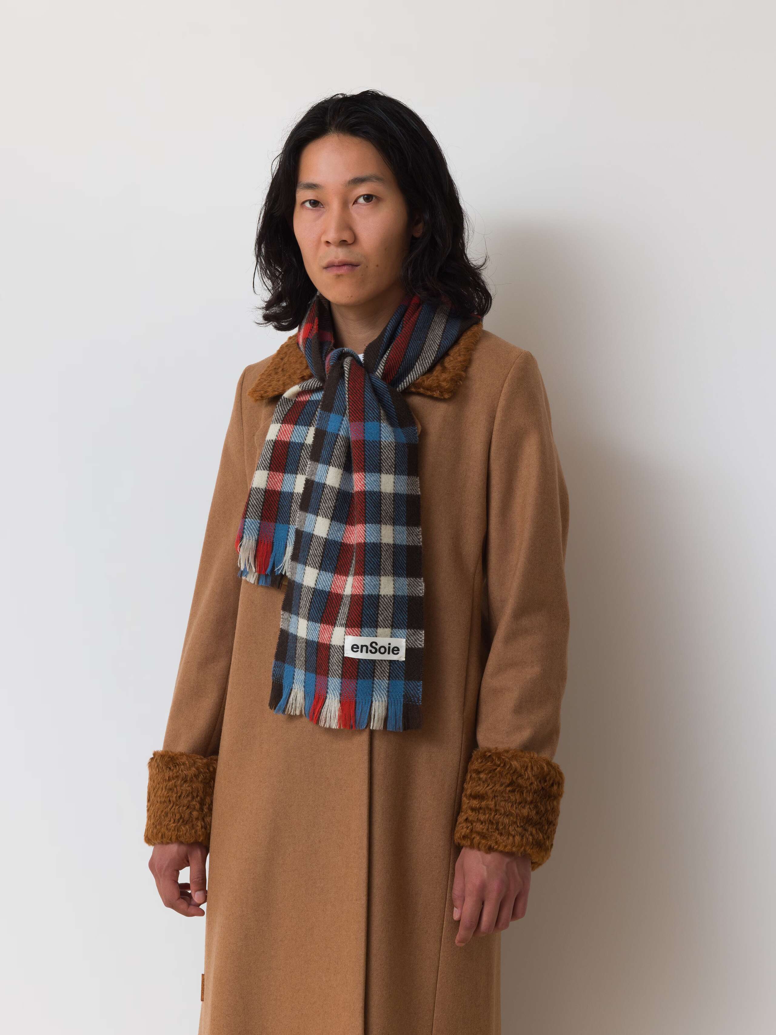 Picture of a male model wearing a beige wool scarf in combination with a colourful wool scarf