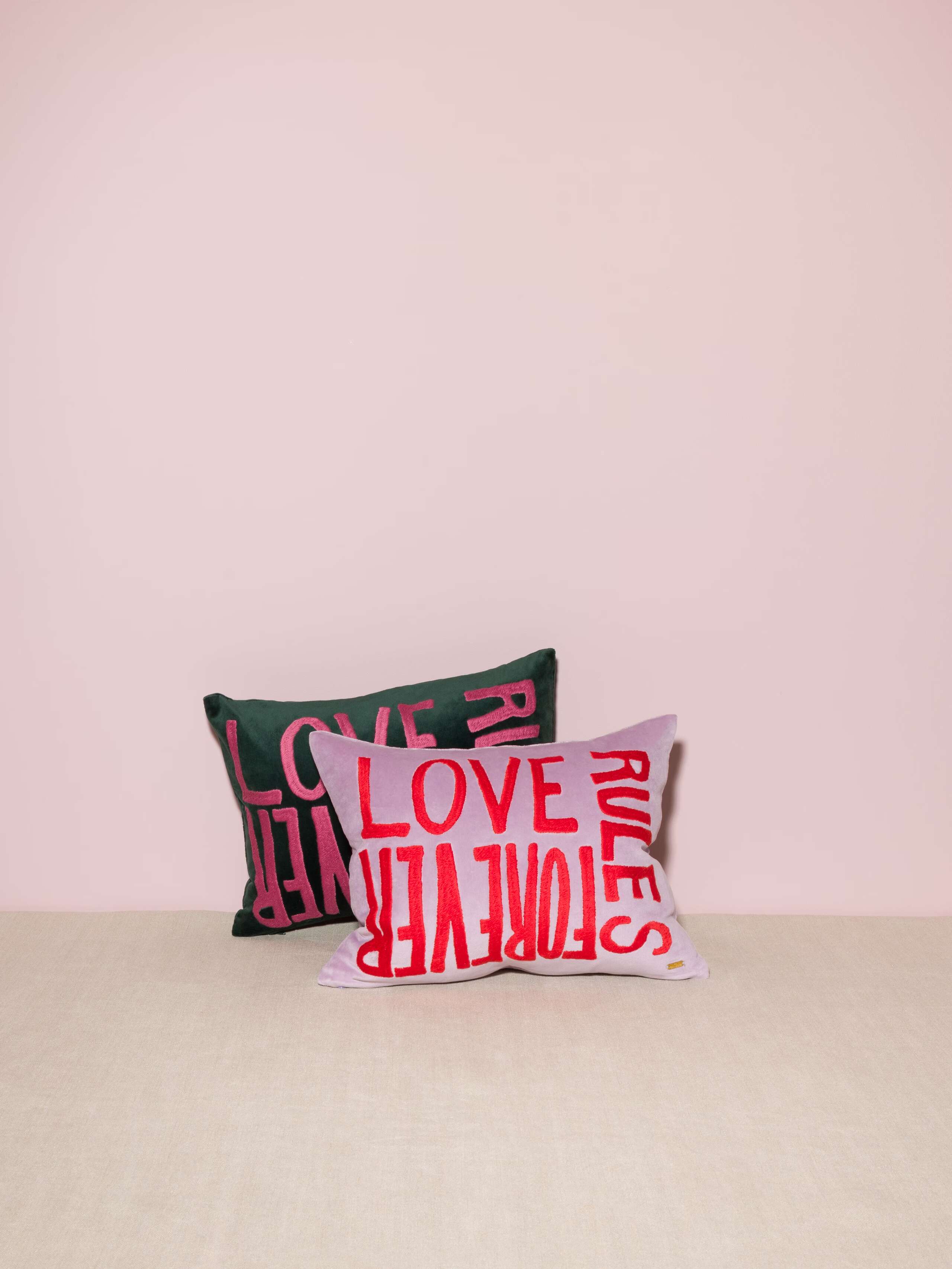 Picture of two beautiful velvet pillow covers featuring a colourful LOVE RULES FOREVER emboidery