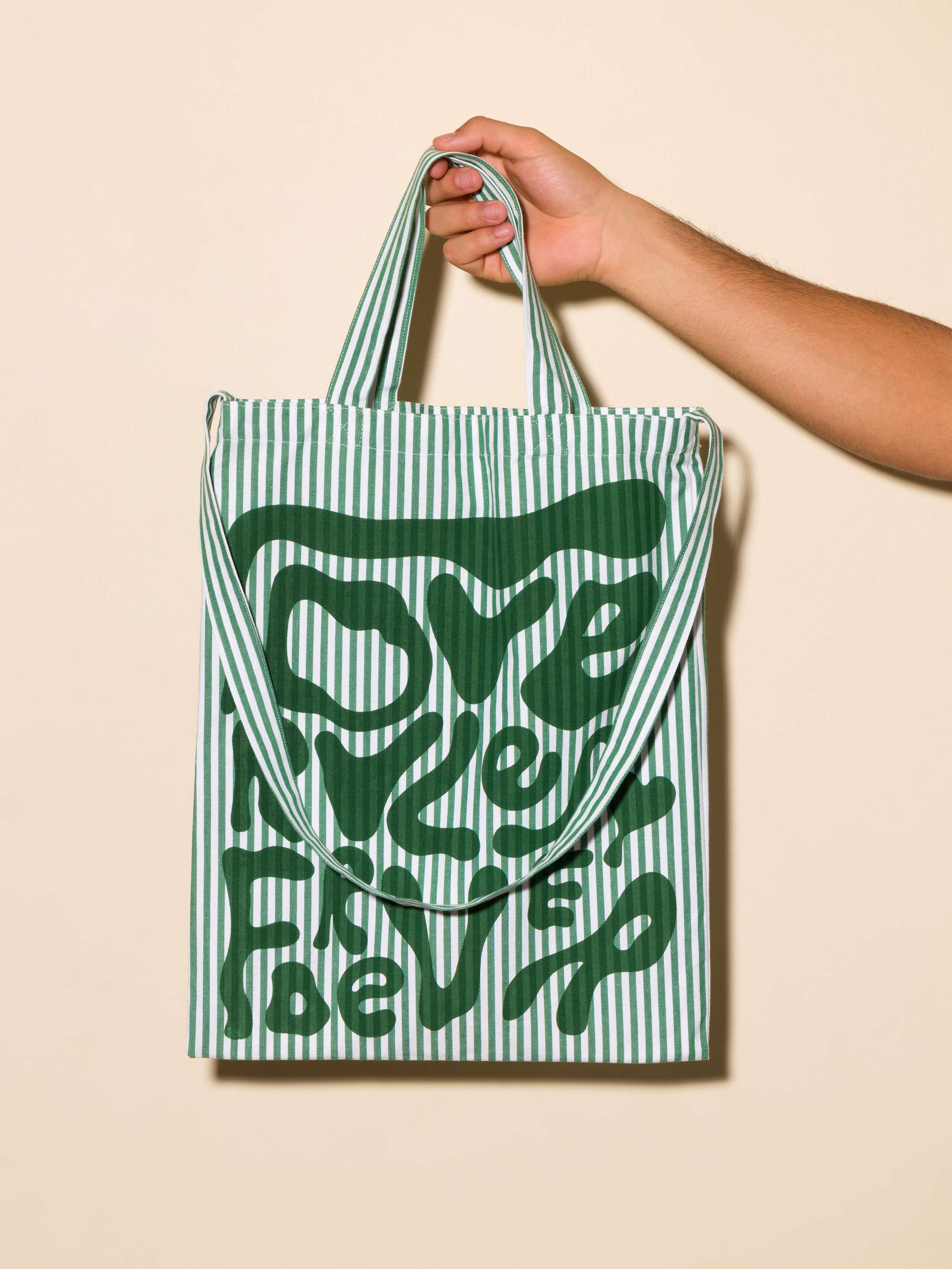 Picture of a green striped tote bag featuring the motto Love Rules Forever