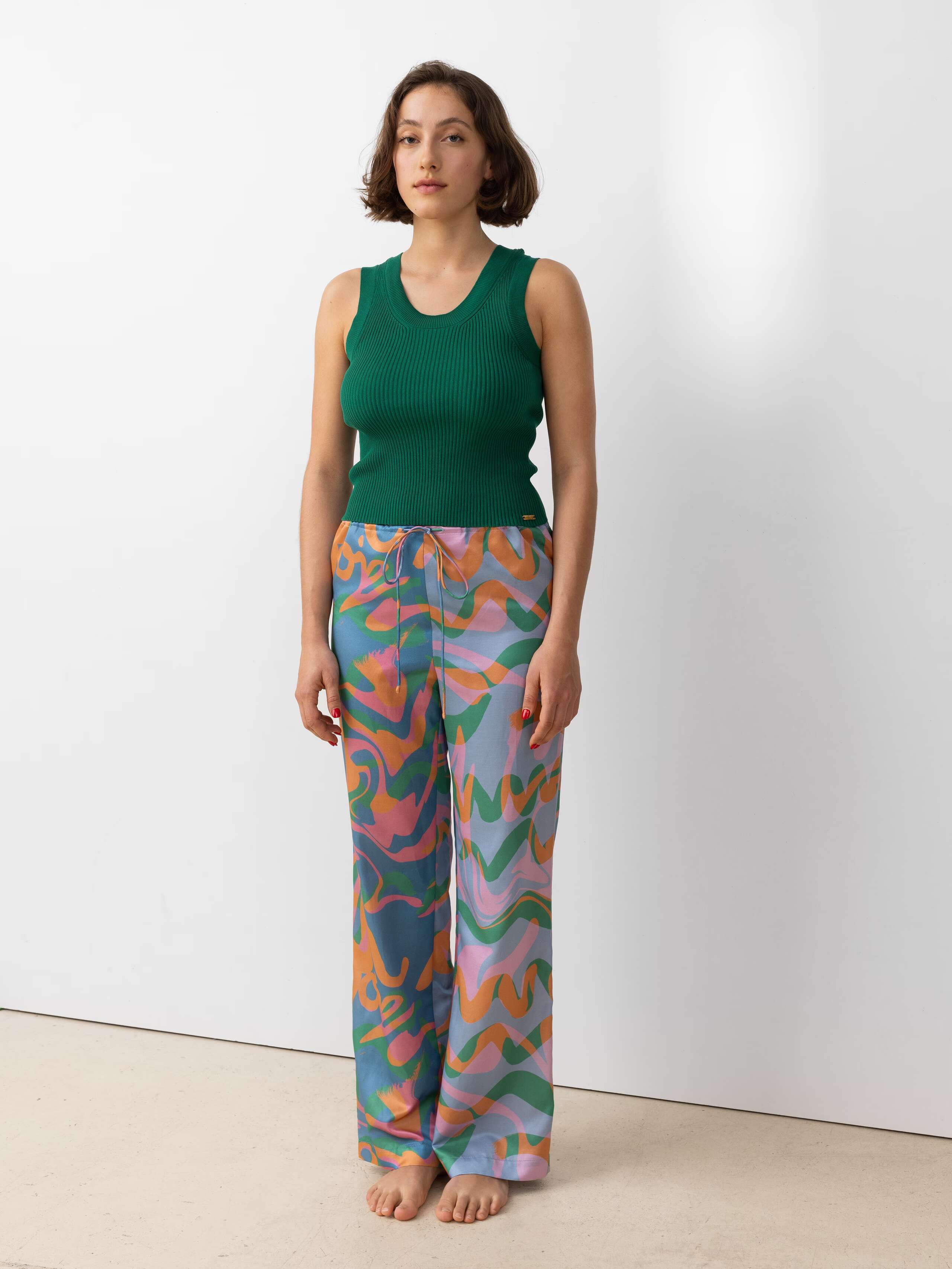 Picture of a model wearing a green knitted top in combination with colourful trousers 