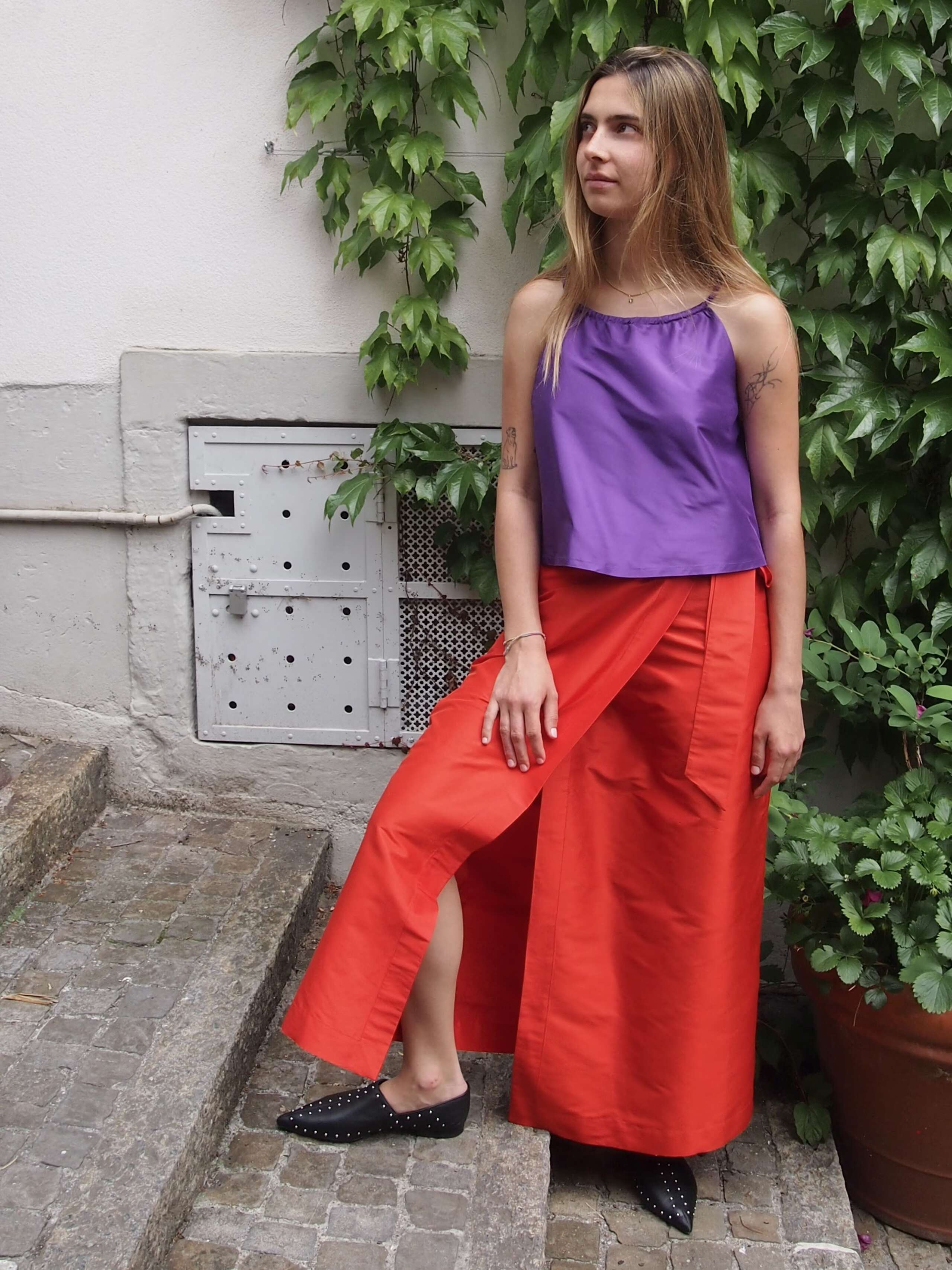 Model is wearing a purple top in combination with a red long skirt