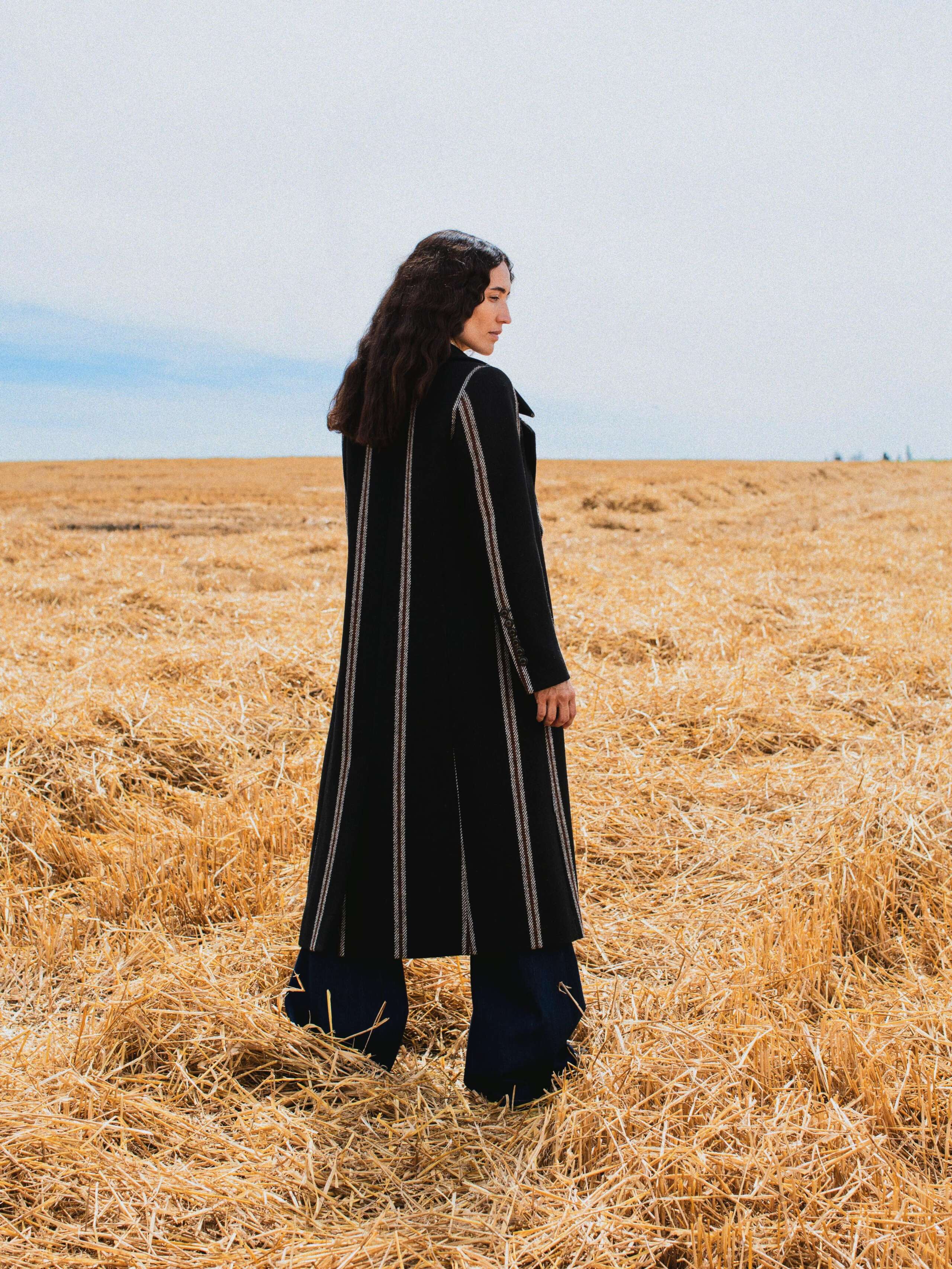 Picture of a female model wearing a black coat made from Harris tweed