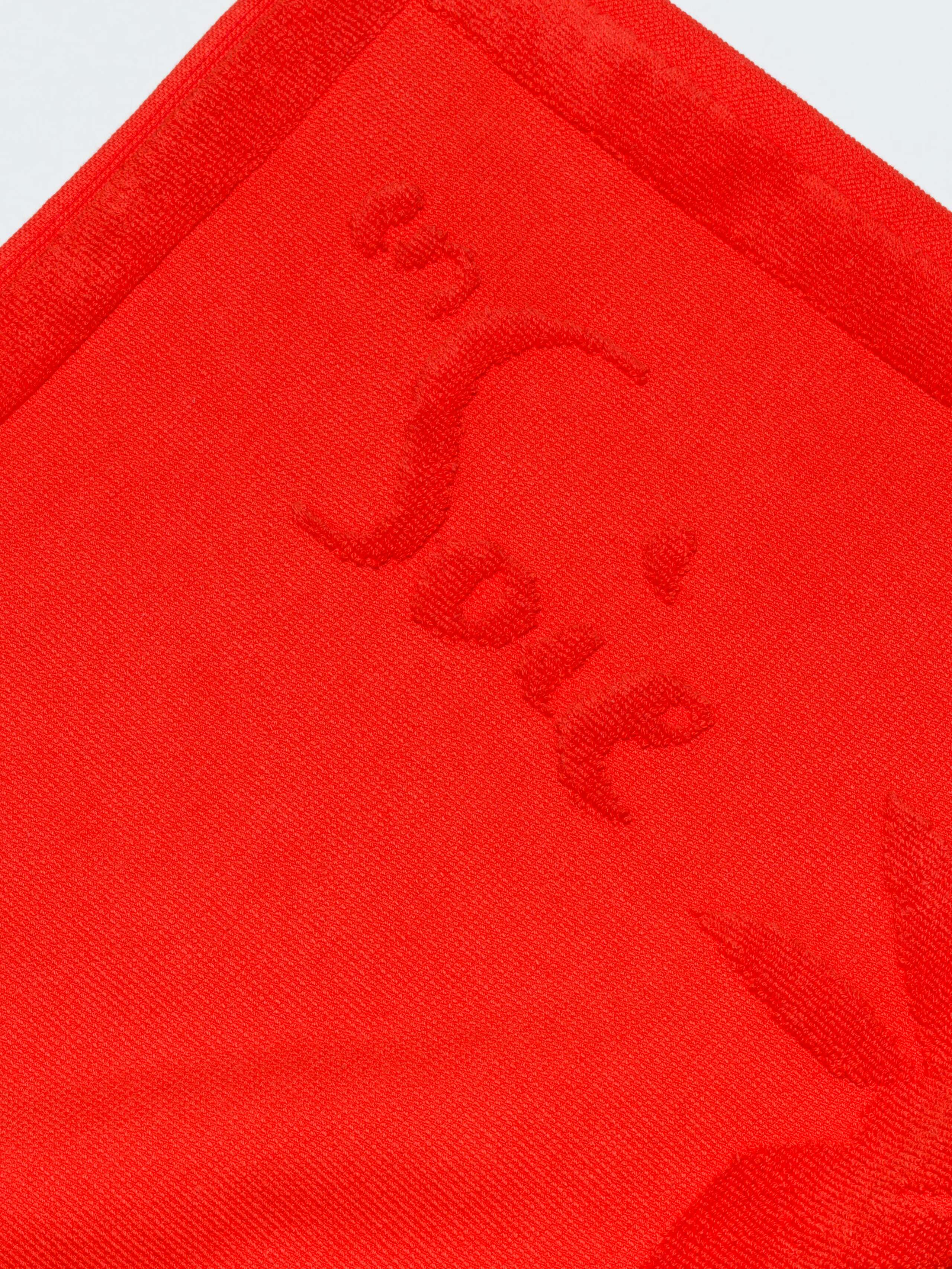 Soft red terry bath mat with rabbits and logo