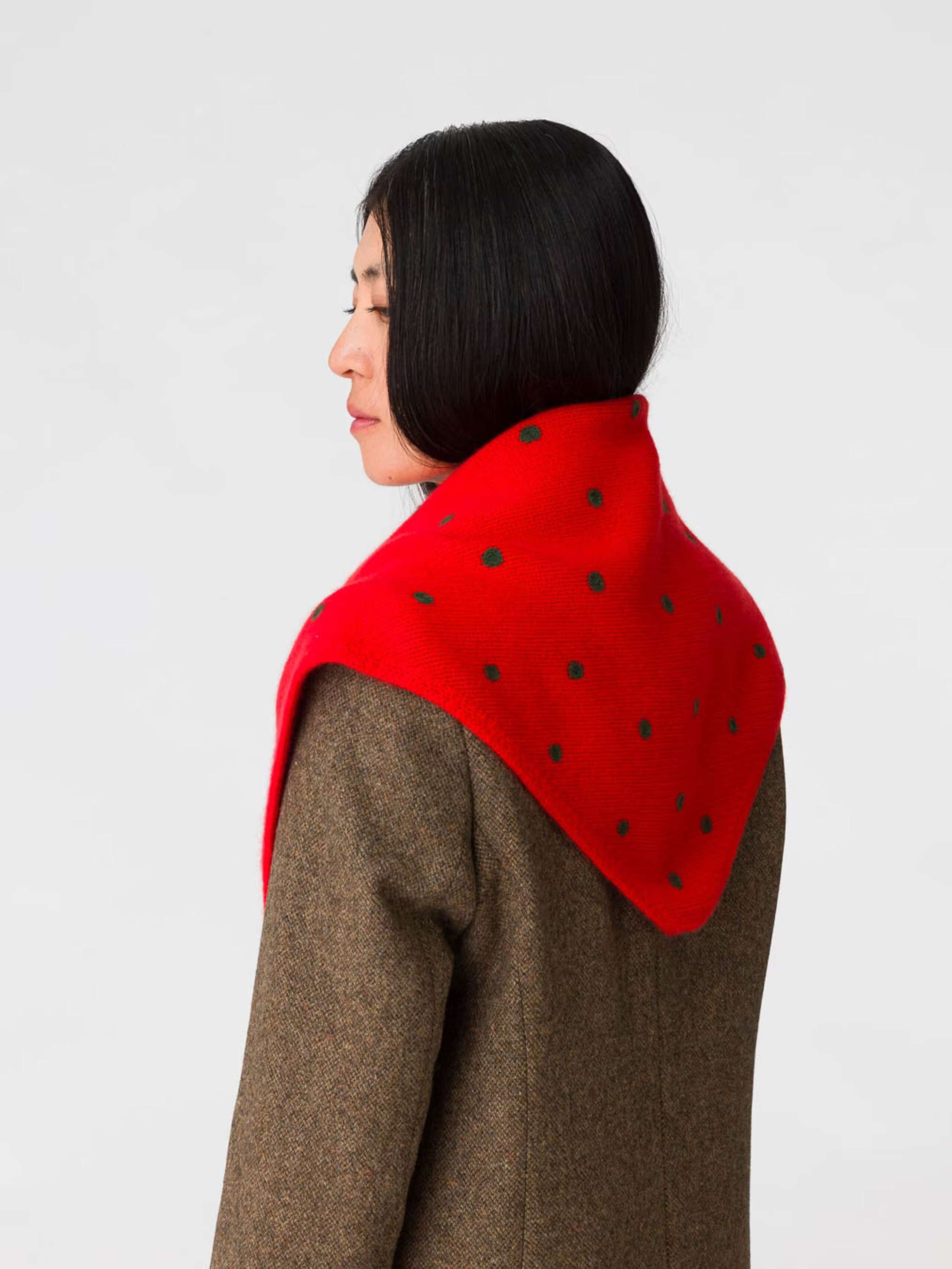 Picture of a women wearing a red cashmere scarf featuring green dots