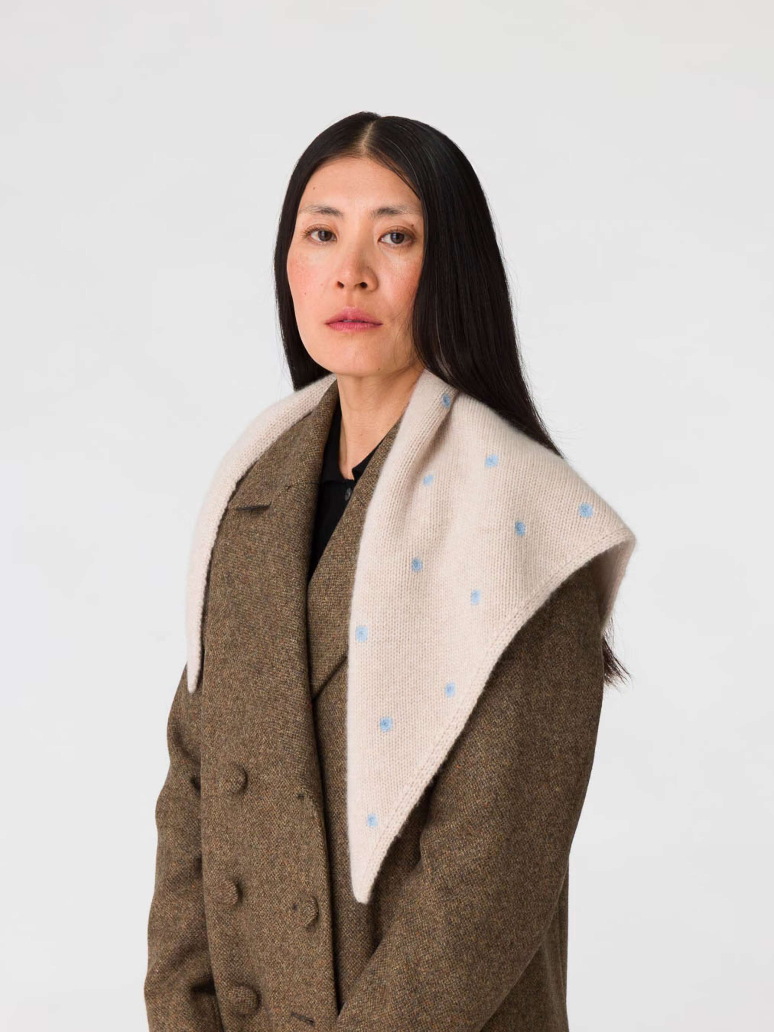 Picture of a women wearing a beige cashmere scarf featuring light blue dots