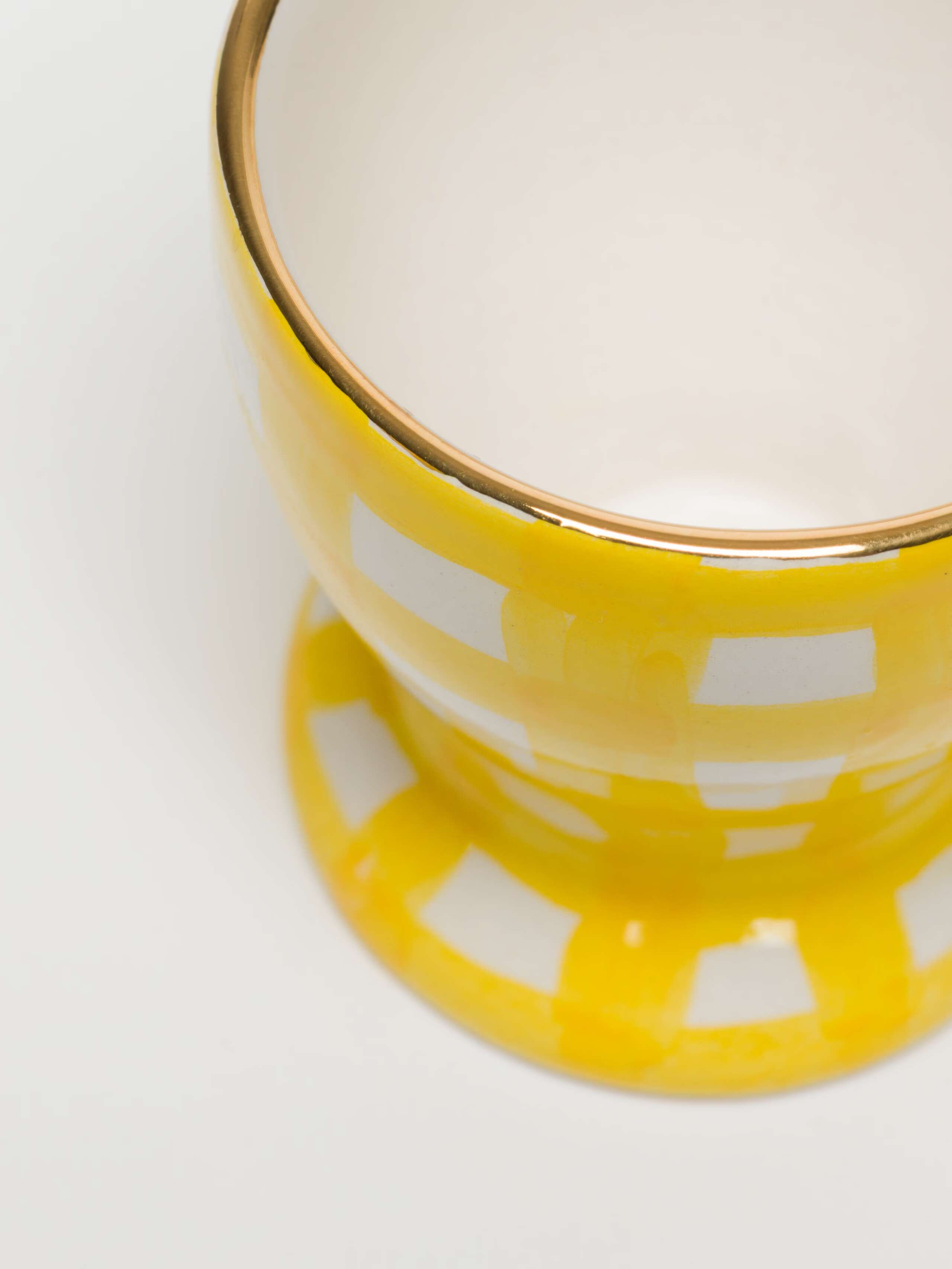 overhead detail shot of gold rim on greta egg cup in sunny yellow