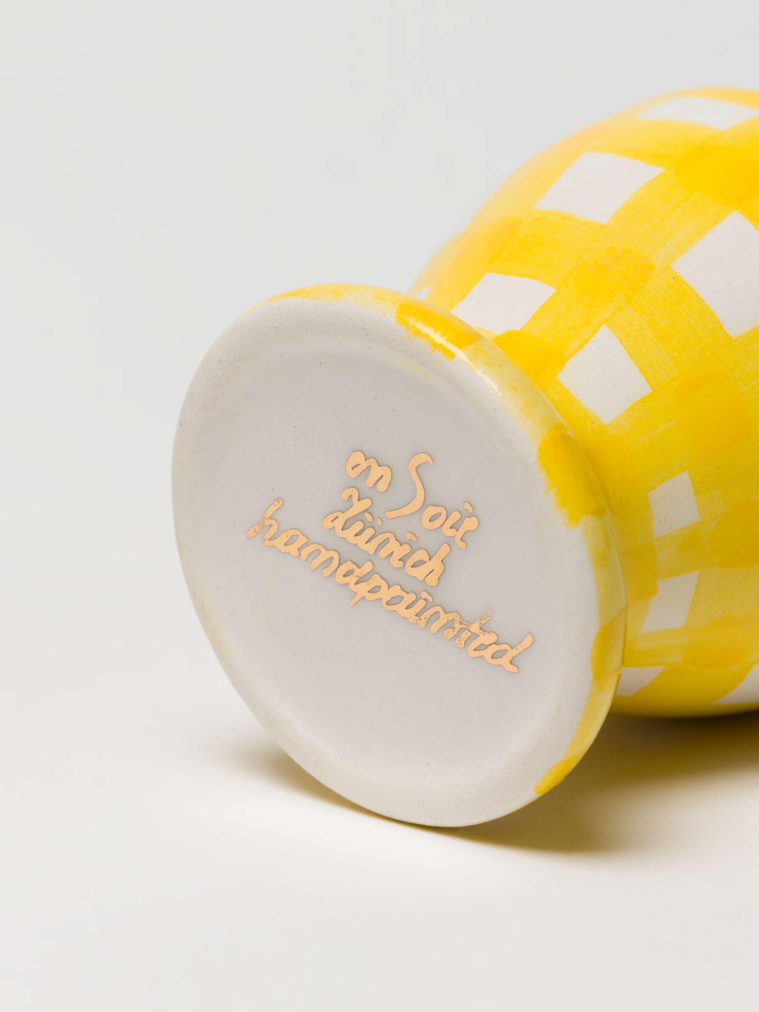 detail shot of hand-painted logo on bottom of Greta egg cup in sunny yellow