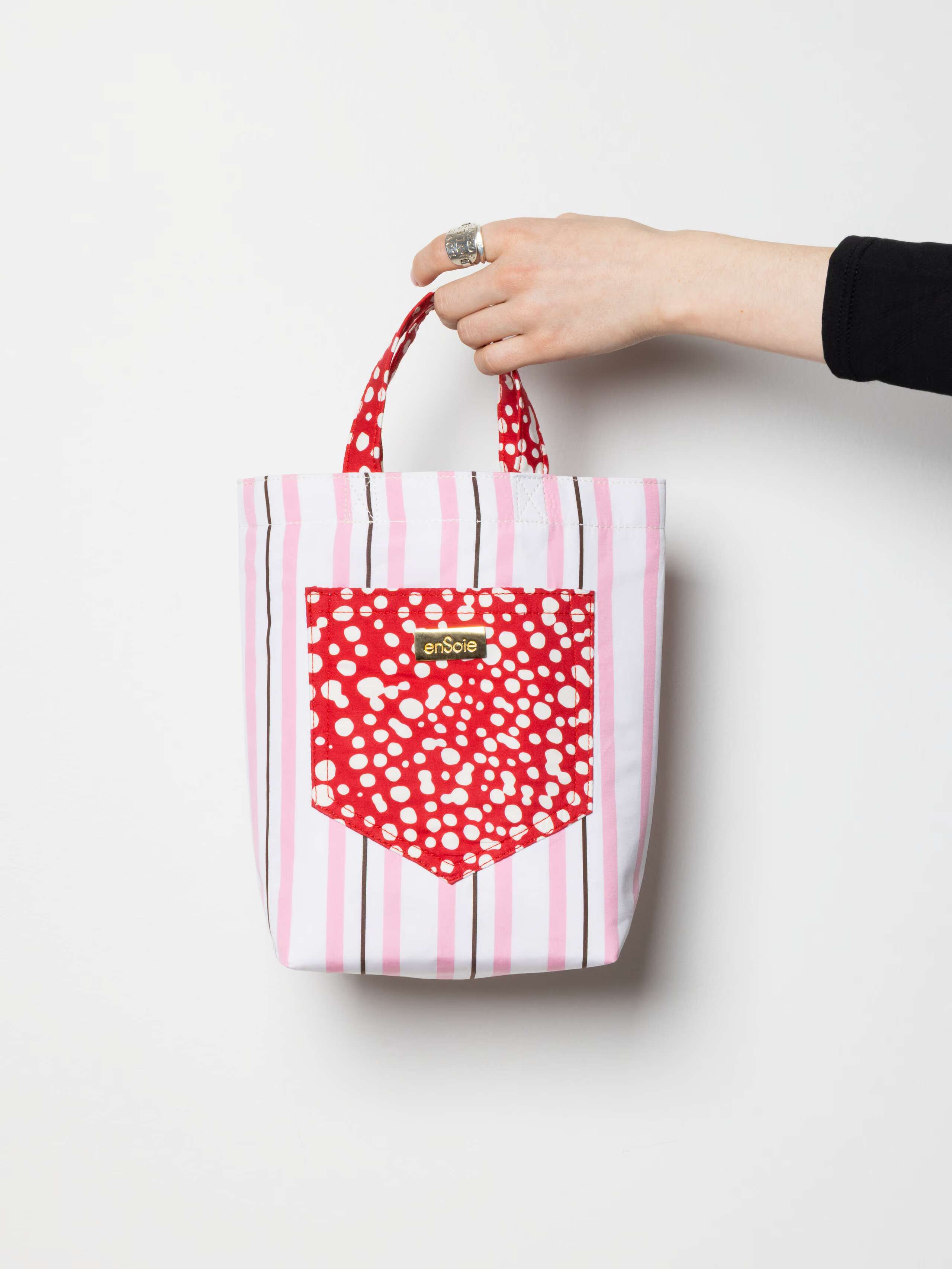 Product shot of June Bag in Rose Stripe with Red Dot accents in hand 