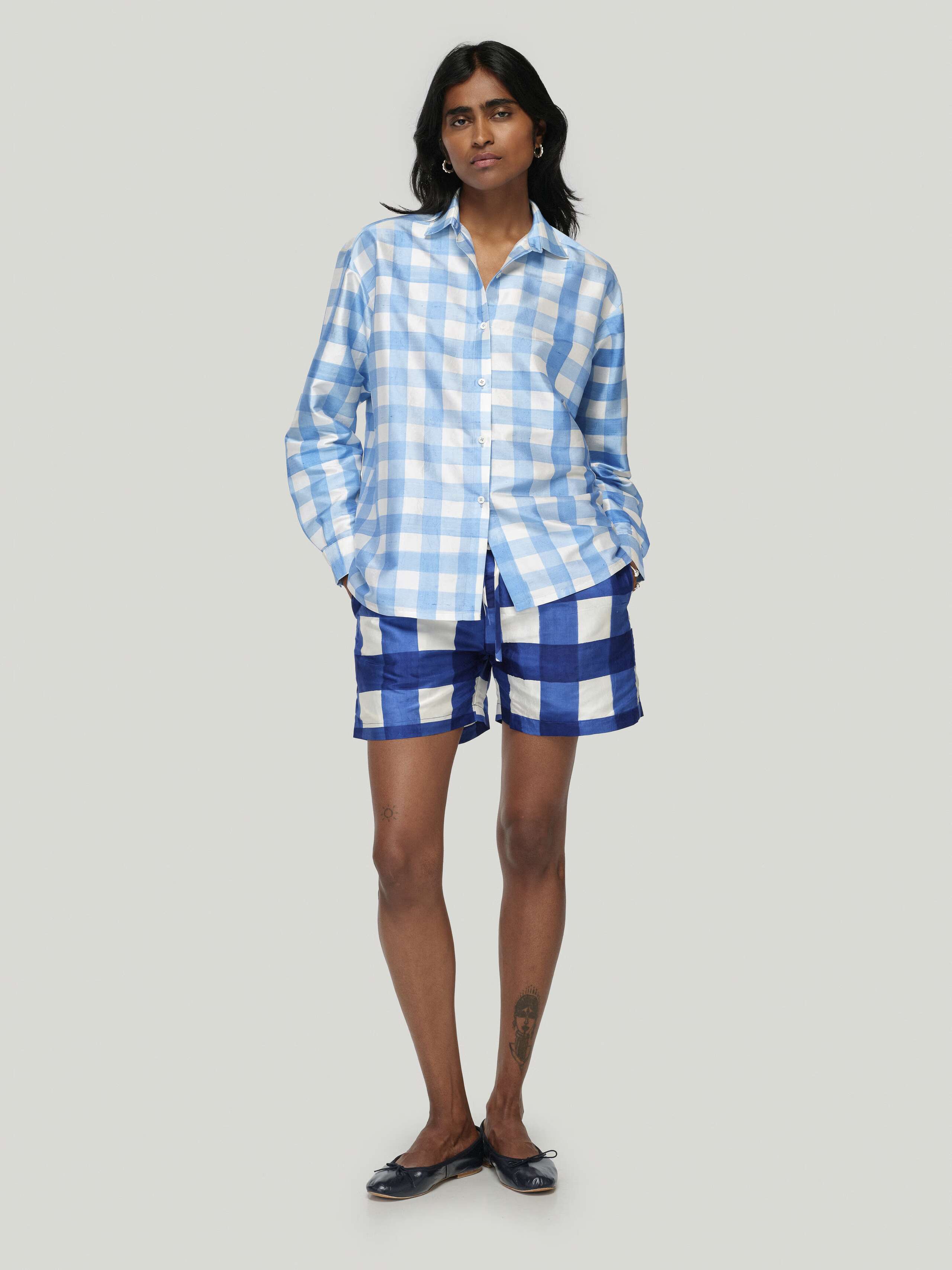 Female model wearing Francesca blouse in ocean blue paired with allen shorts in zurich navy