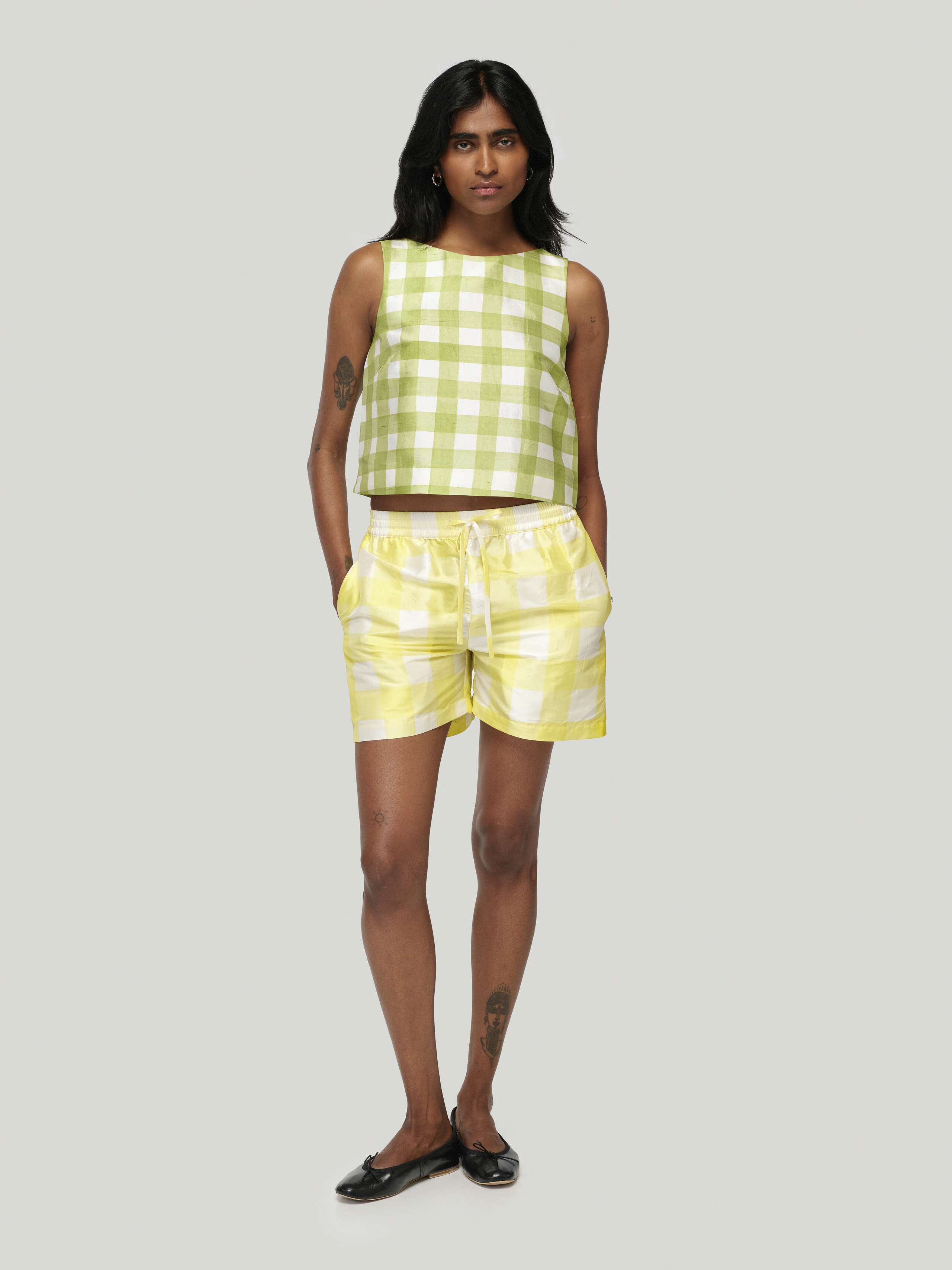 Female model wearing Junko Top in green and allen shorts in yellow