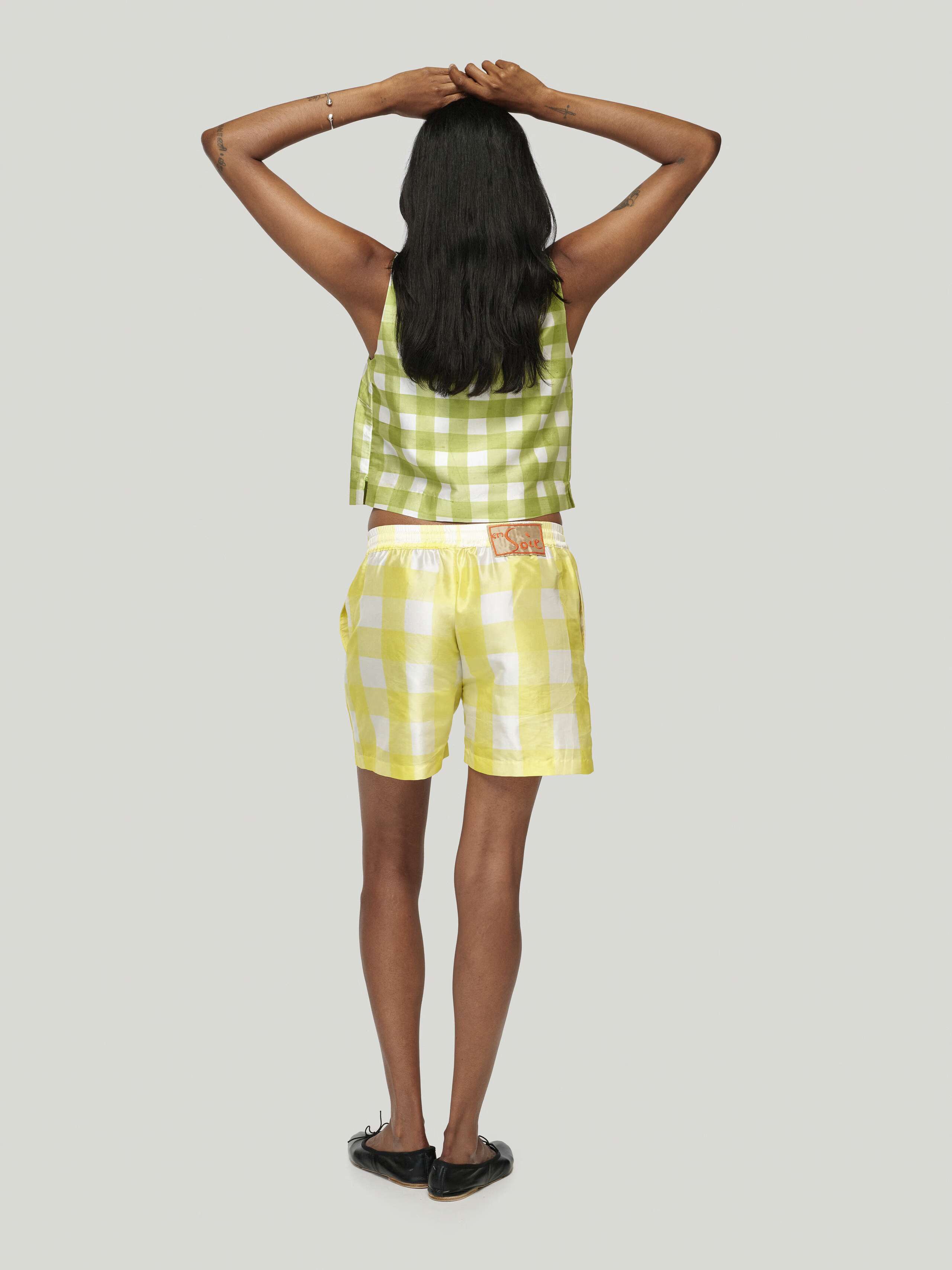 Female model wearing Junko Top in green and allen shorts in yellow