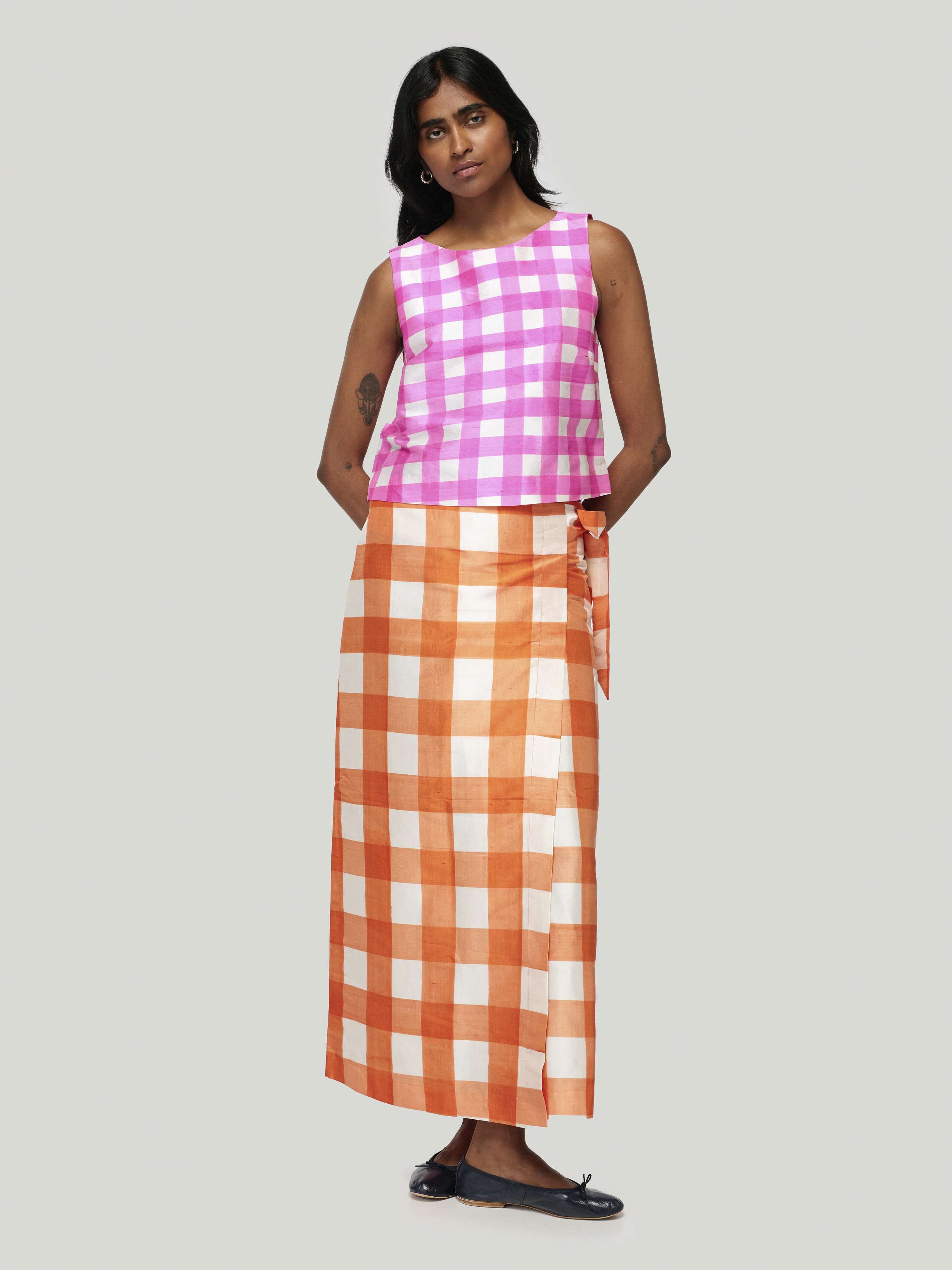 Model wearing edina long skirt handpainted vichy in tangerine, combined with junko top in pink