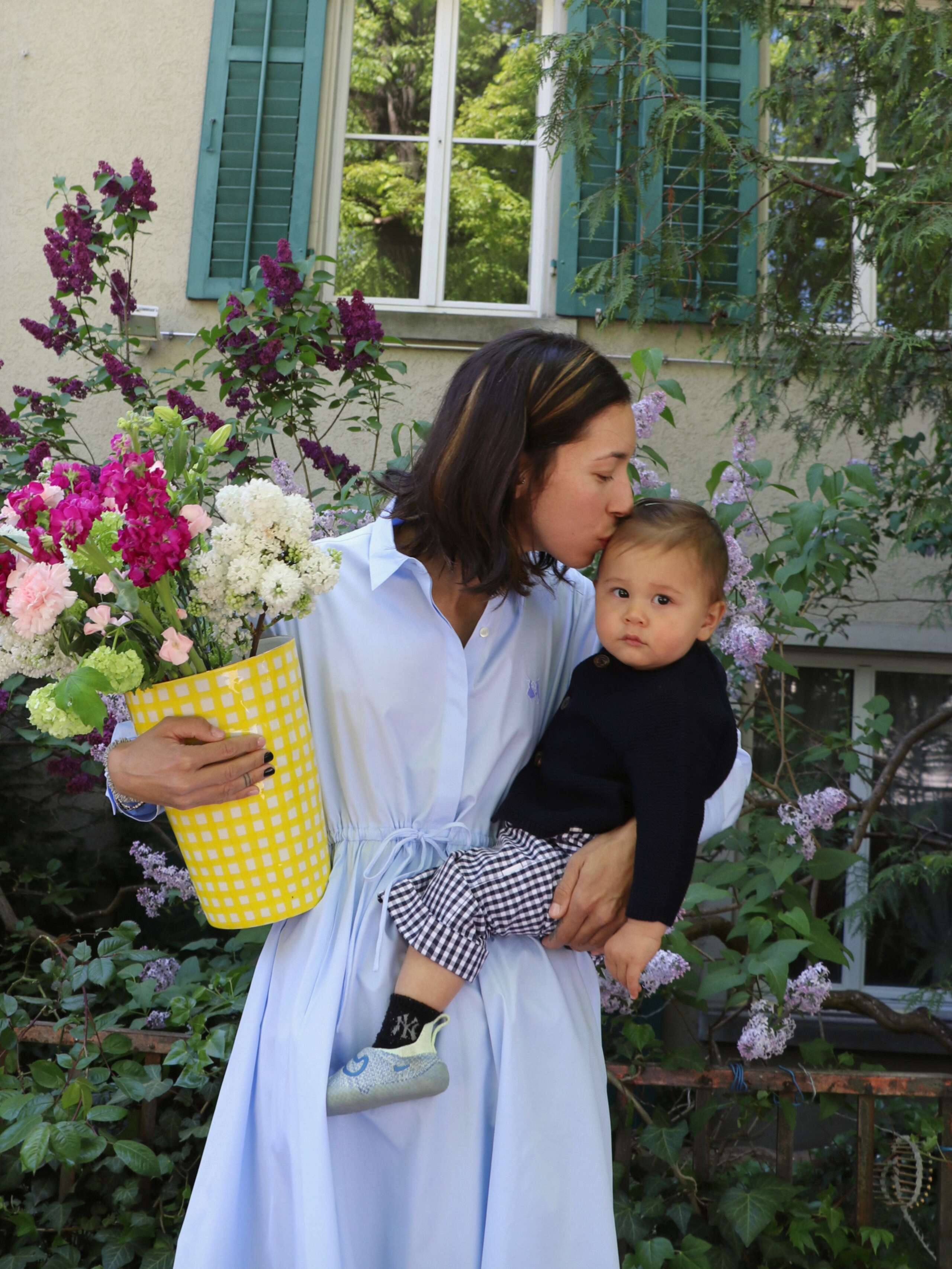A mother with her small son on her arm, holding a vase filled with flowers