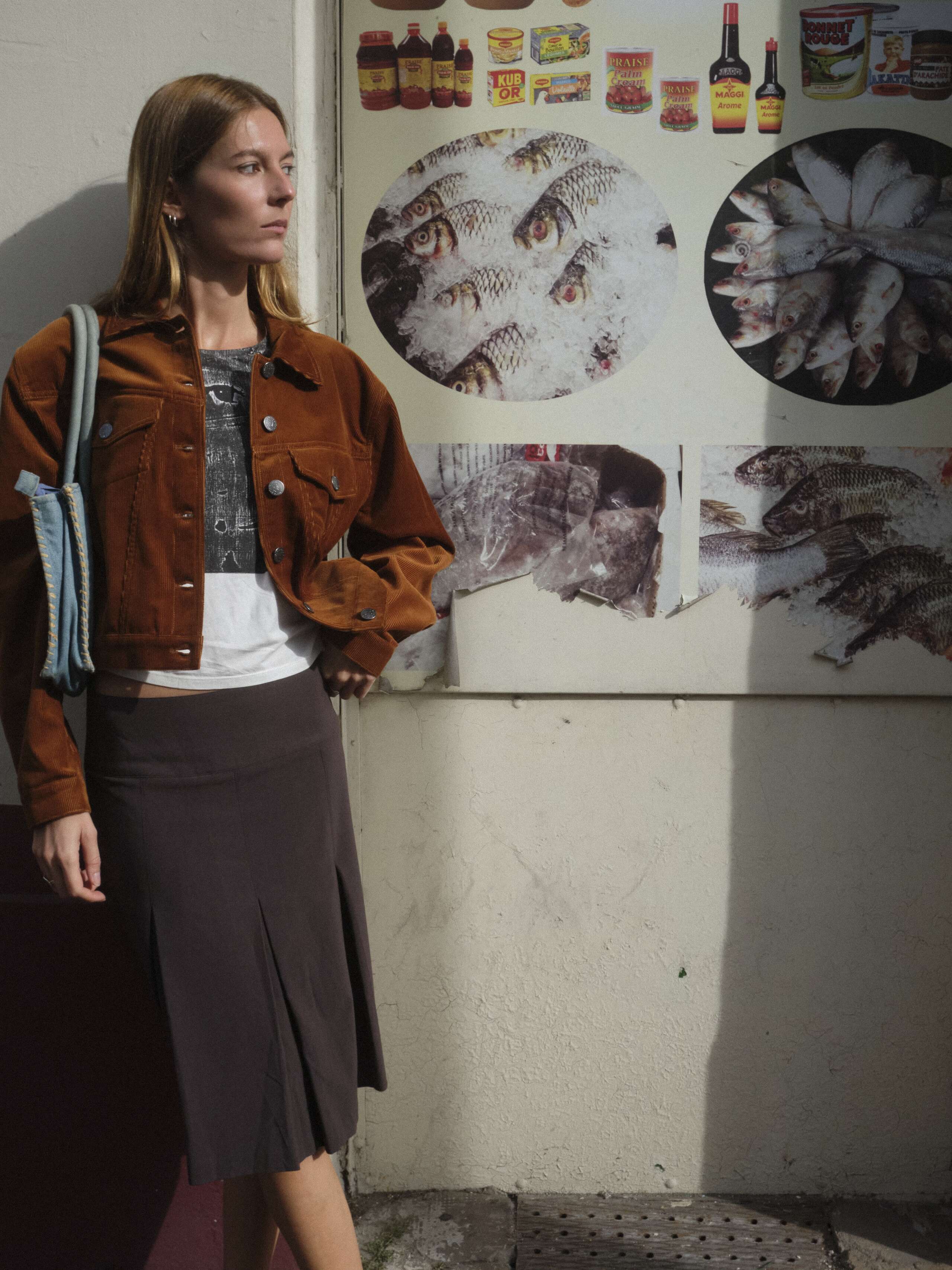 A young women is standing in front of a wall wearing the enSoie Jill jacket
