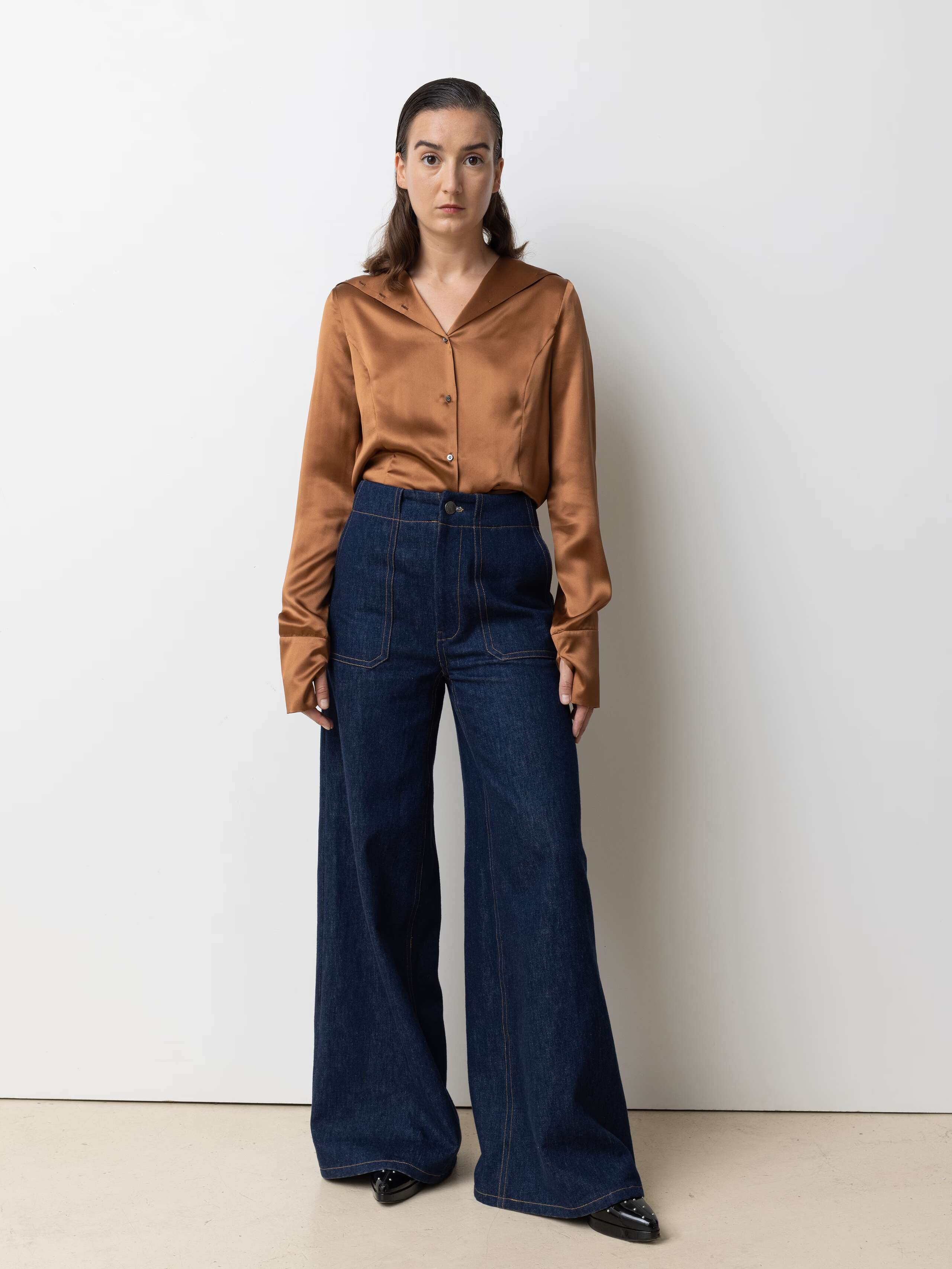 Picture of a female model wearing blue jeans in combination with a shiny brown silk blouse