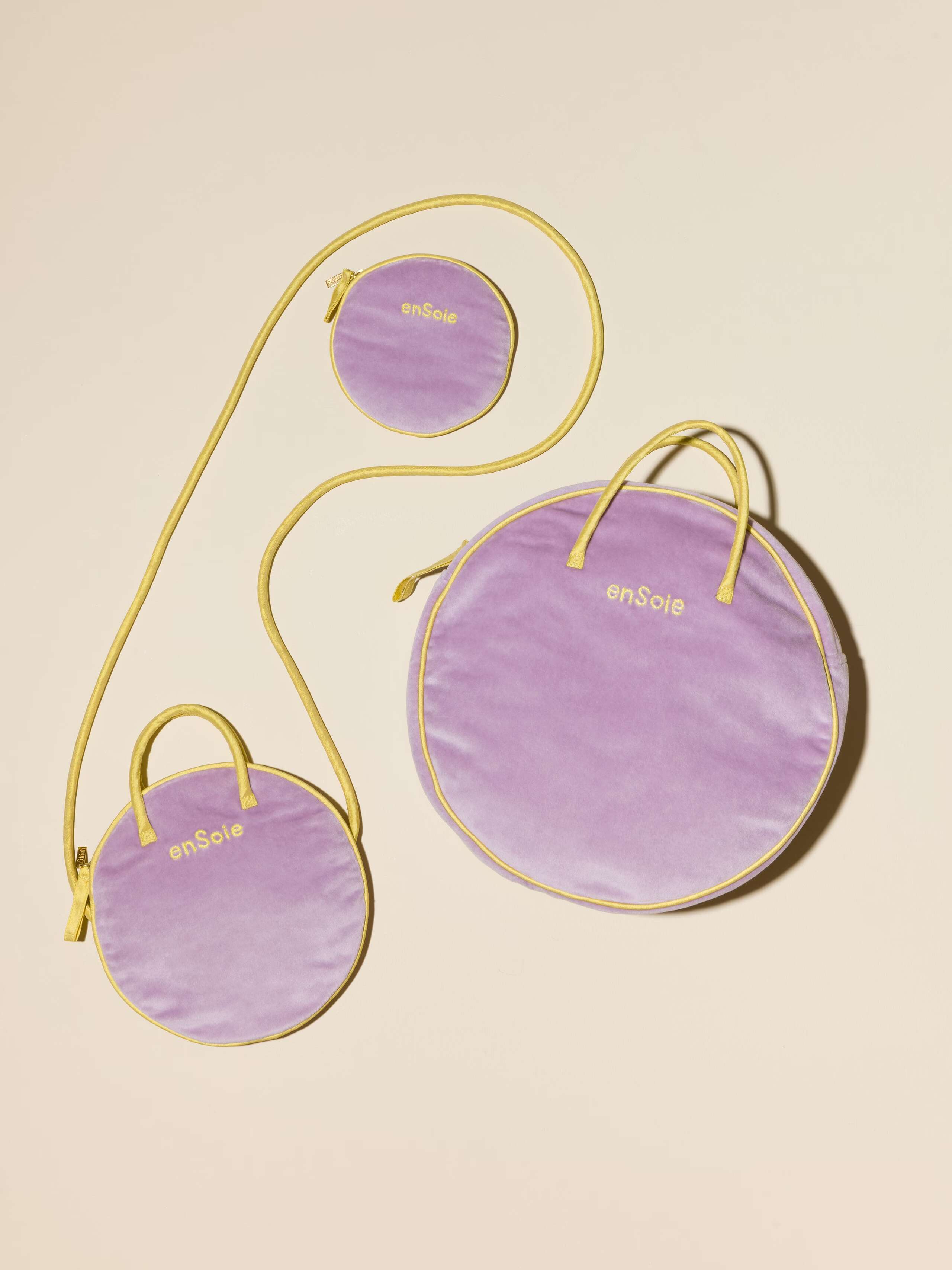 Picture of three round bags in three different sizes made of velvet in a beautiful lavender shade featuring yellow silk handles