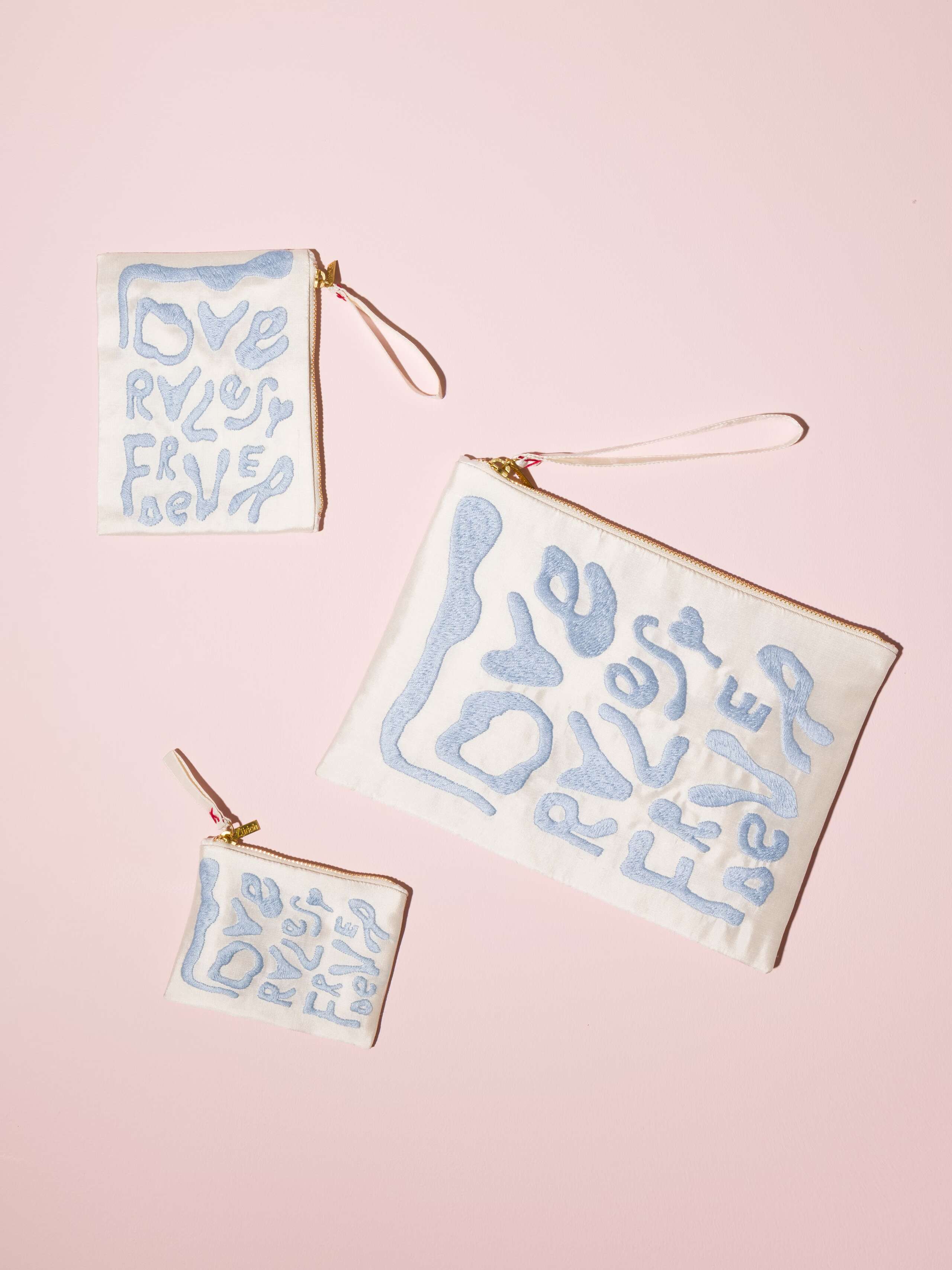 Picture of three white silk clutches featuring a beautiful Love rules forever emboridery