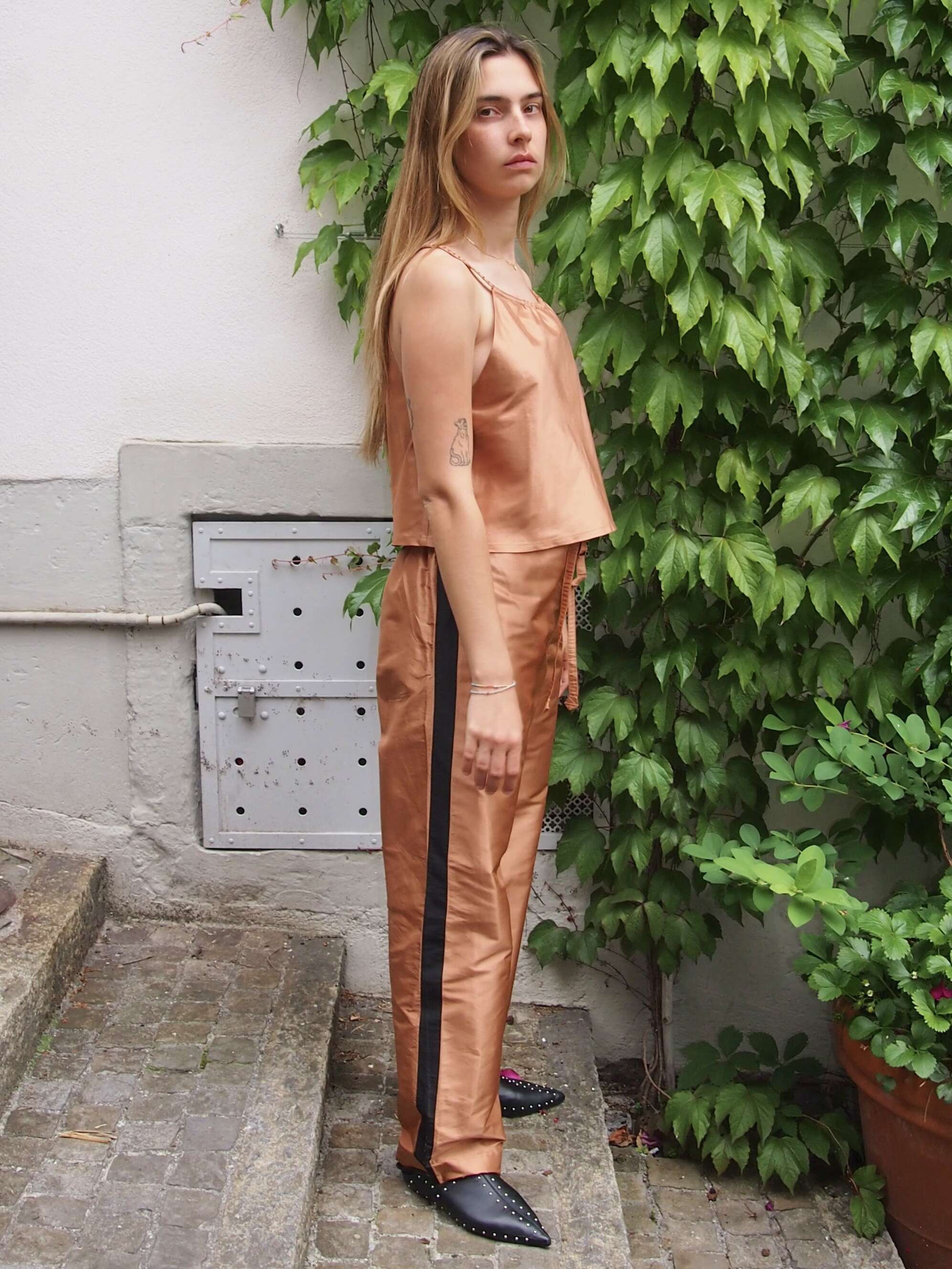 Picture of a female model wearing a brown silk trousers in combination with a brown silk top