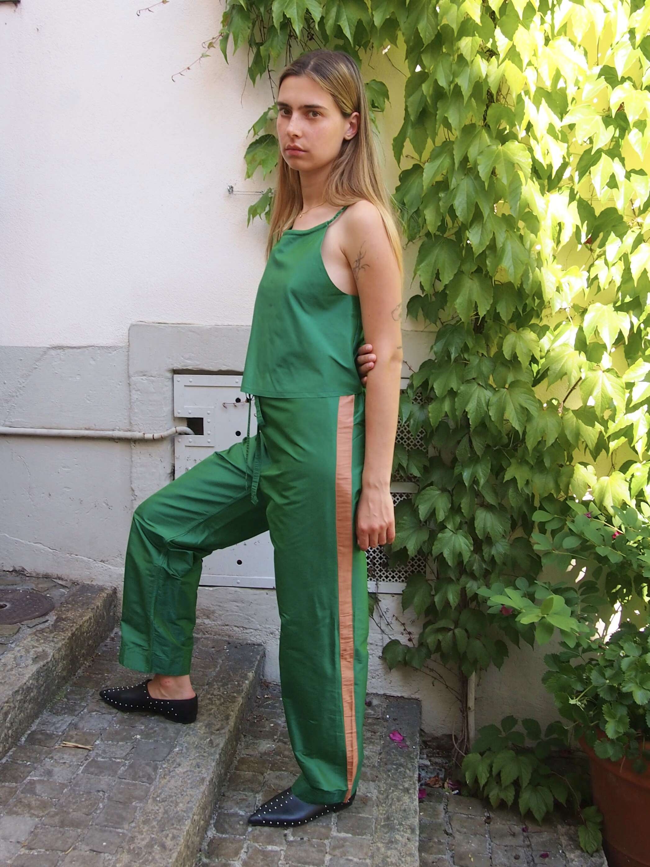 Picture of a female model wearing a green silk trousers in combination with a green silk top