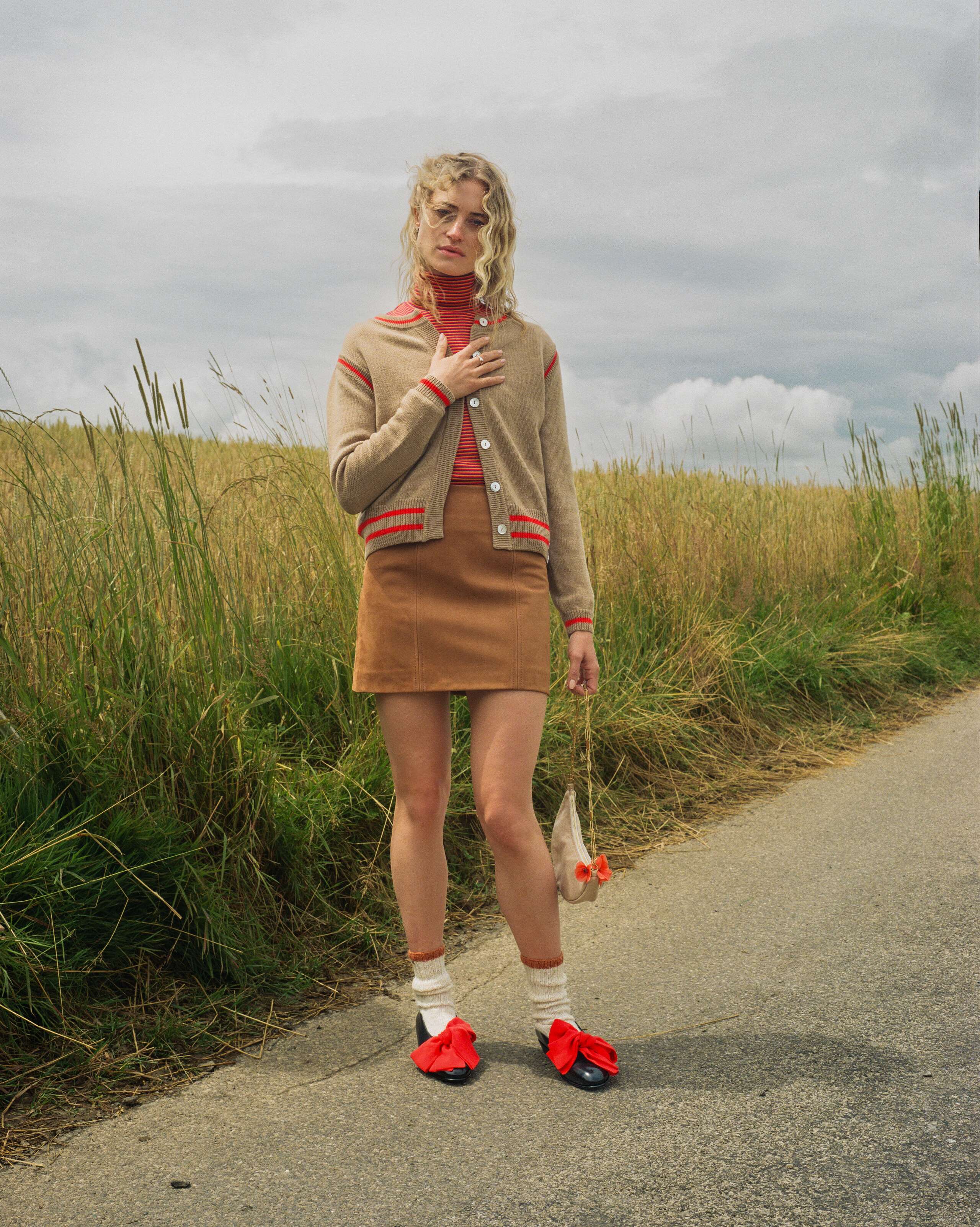 Picture of a female model wearing a beige cardigan in combination with a leather skirt