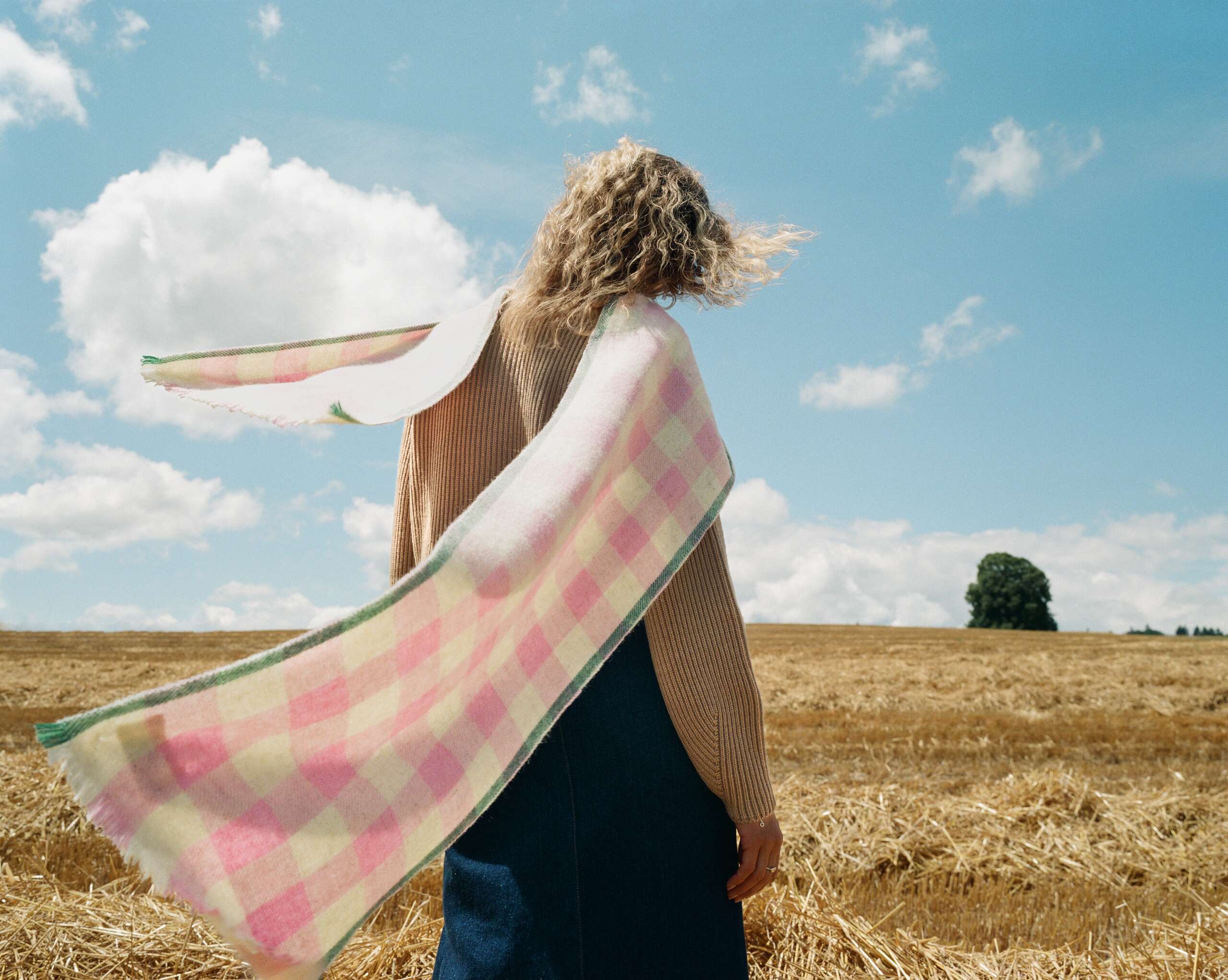 Picture of a female model wearing a cashmere scarf featuring a pink check pattern