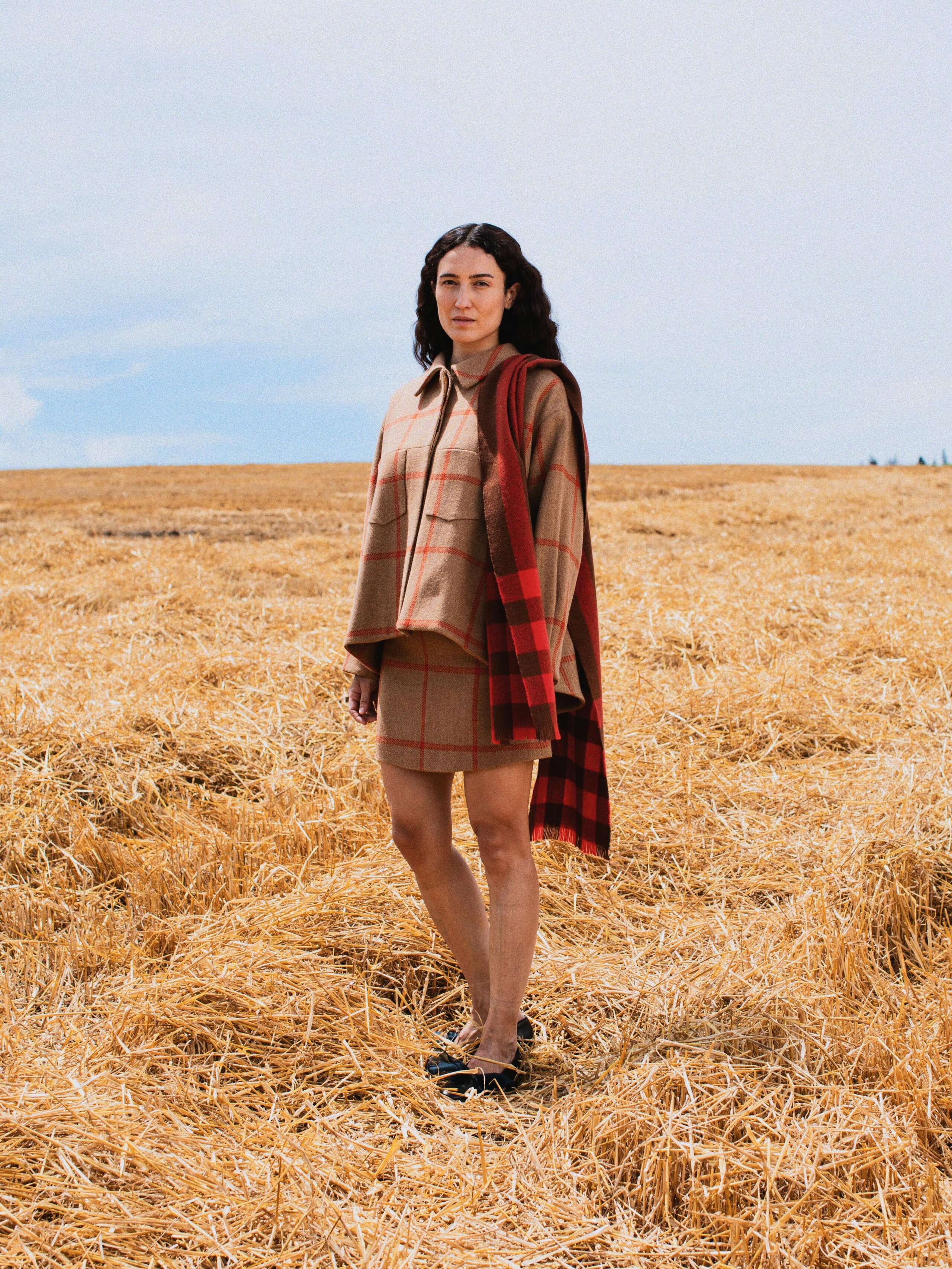Picture of a female model standing in a yellow corn field wearing a beige Harris tweed combination