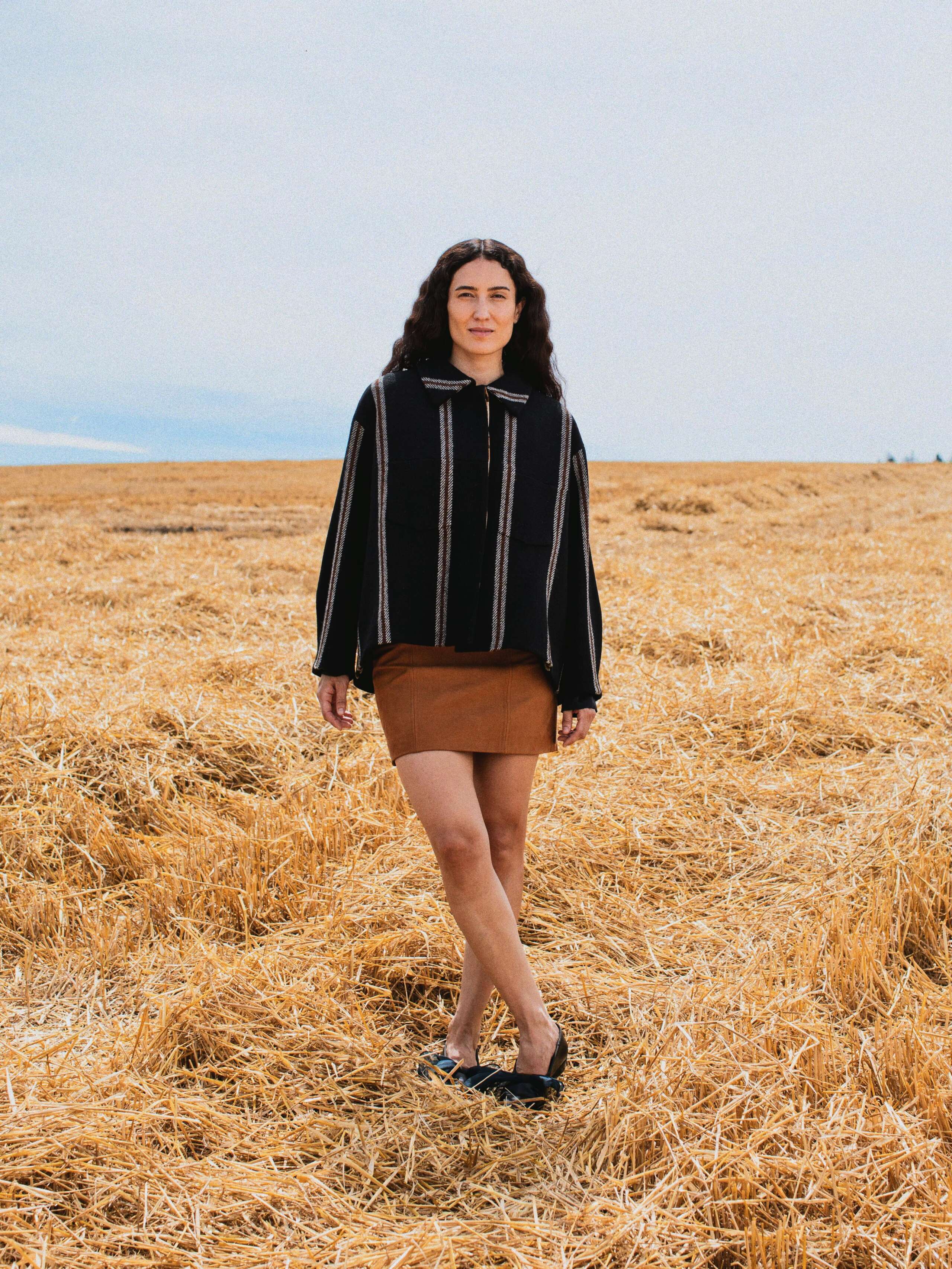 Picture of a female model wearing a brown leather skirt in combination with a black Harris tweed jacket