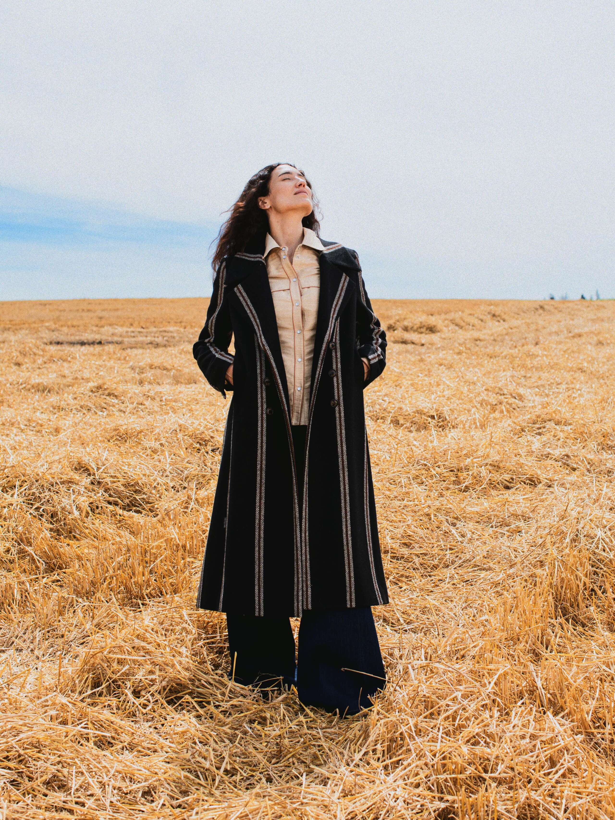 Picture of a female model wearing a black coat made from Harris tweed