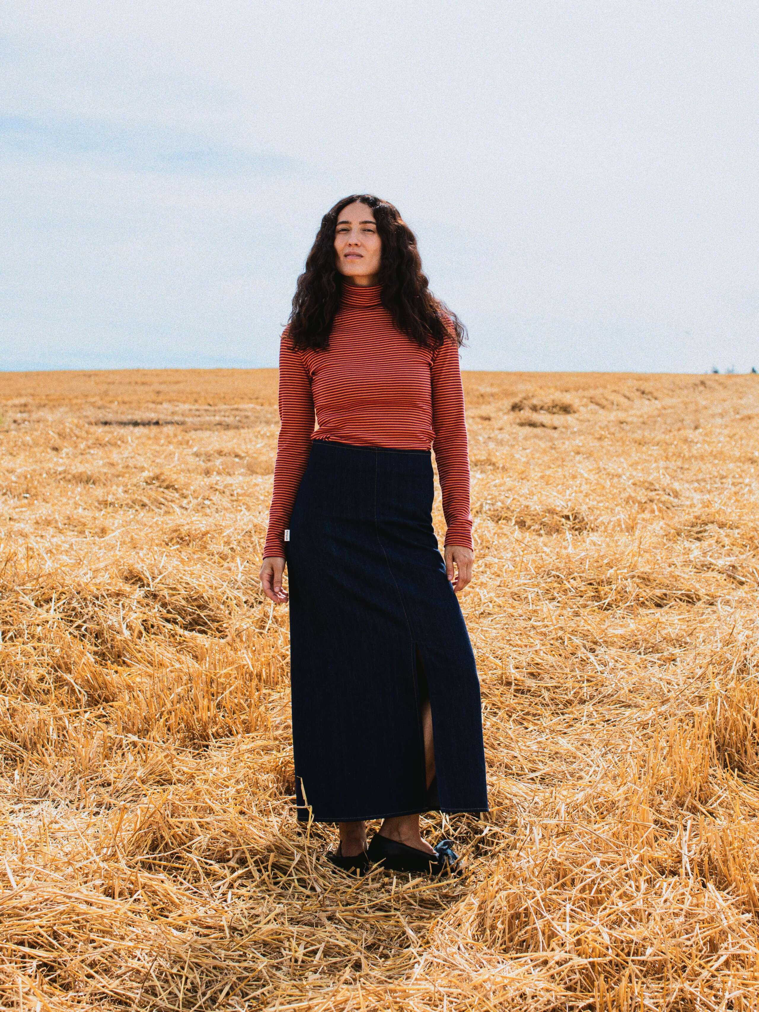 Picture of a female model wearing a denim skirt in combination with a red turtleneck