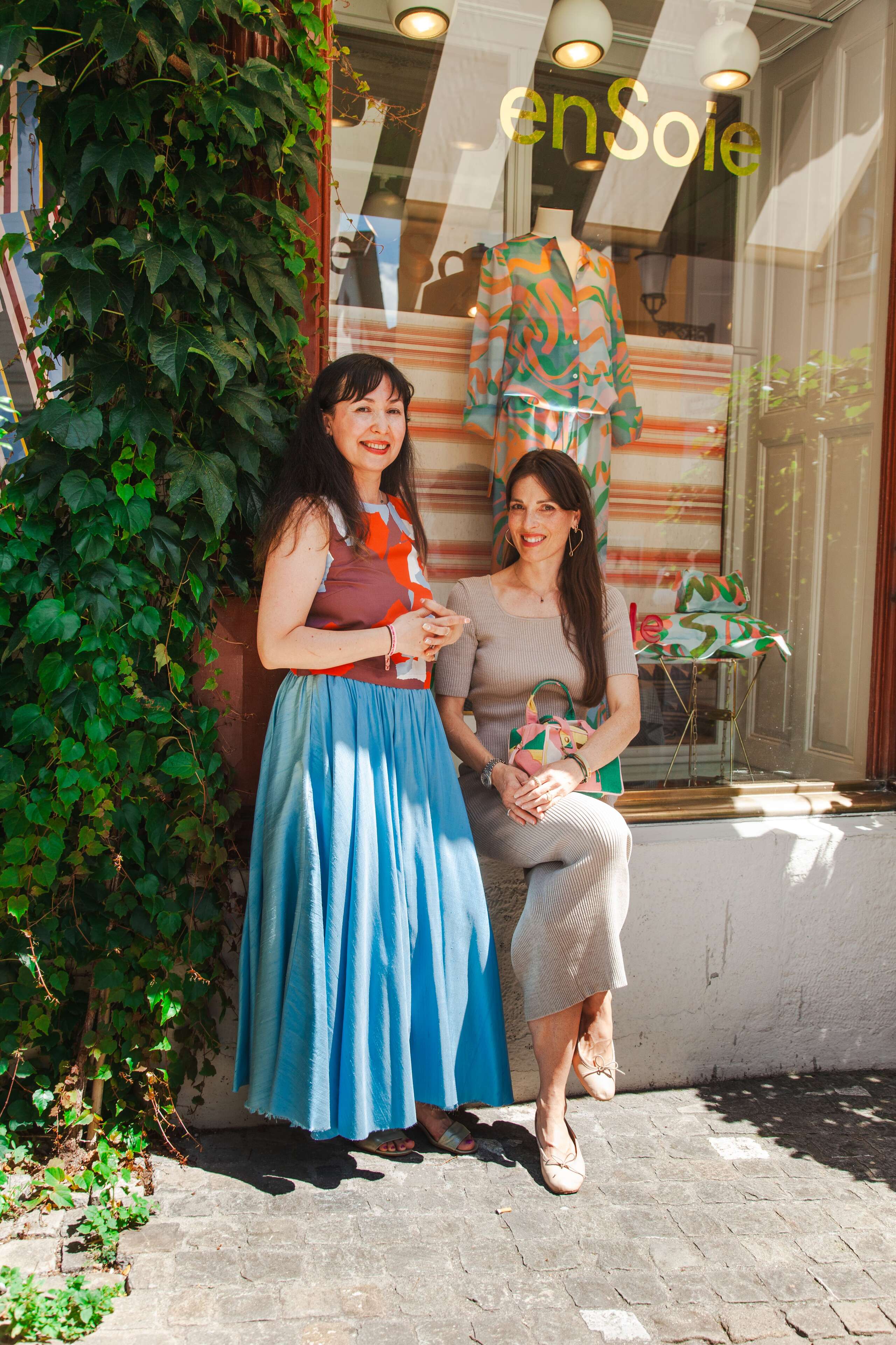 Two women sitting in front of a store