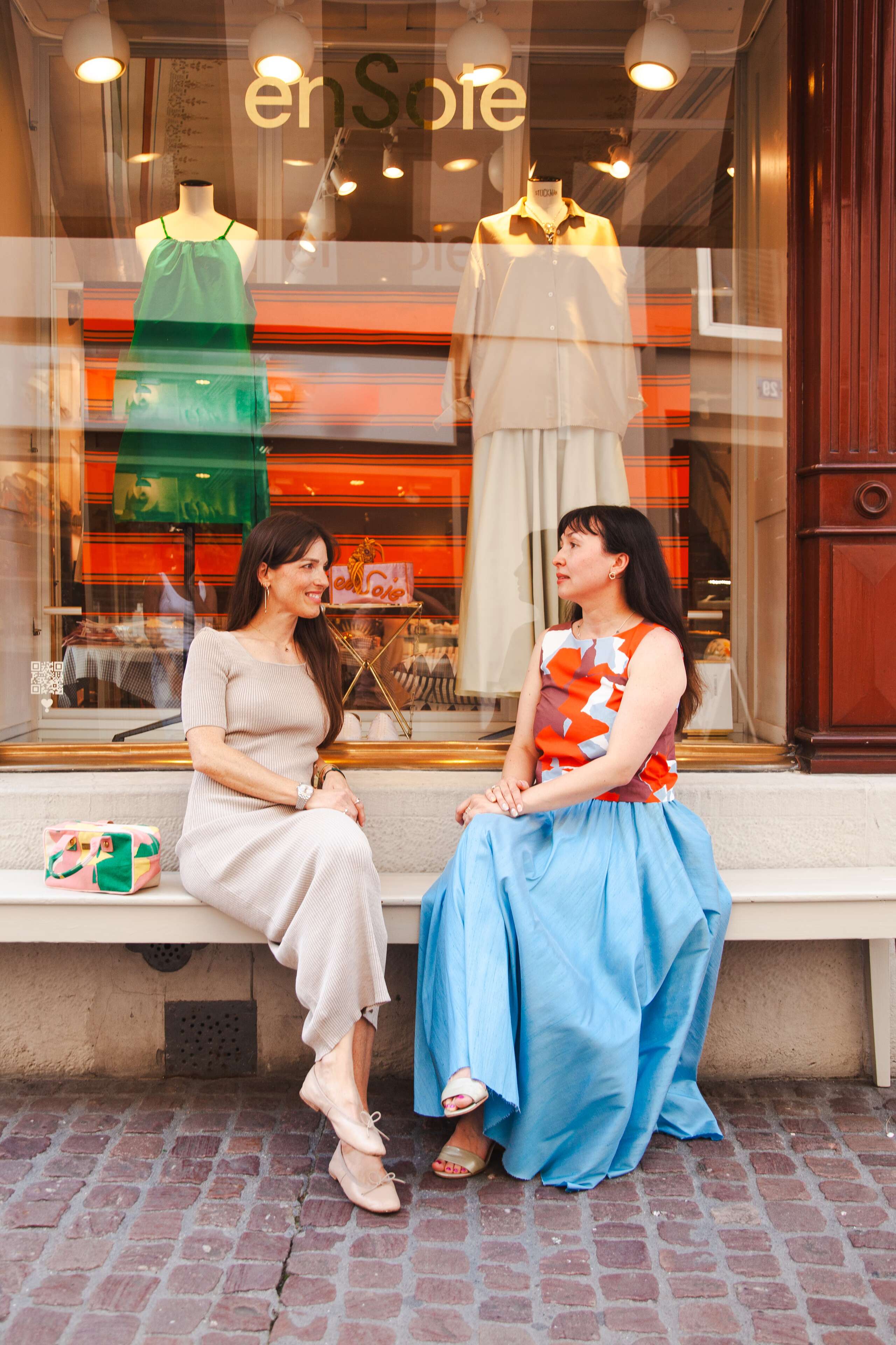 Two women sitting in front of a store