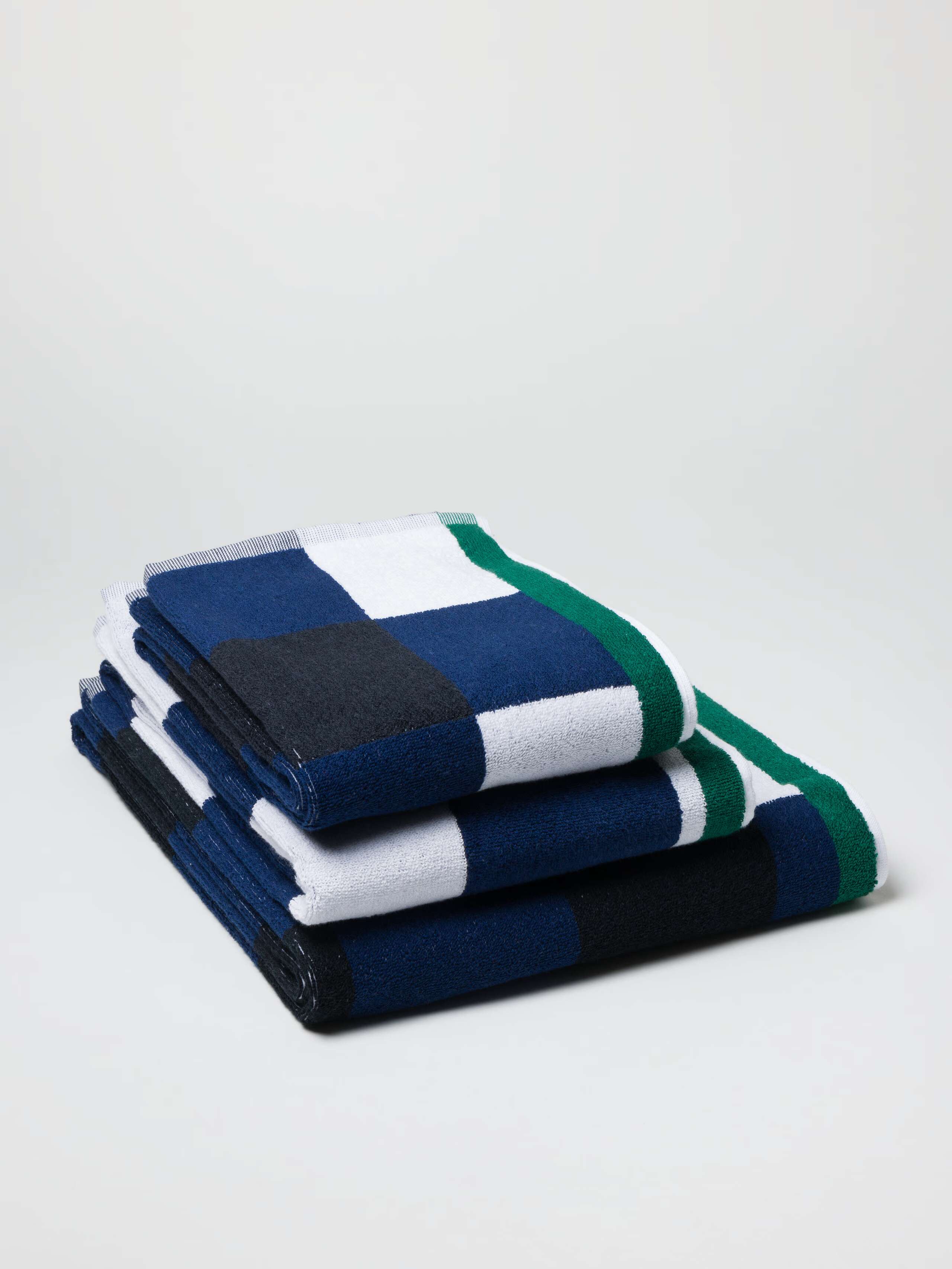Terry bath towel in navy vichy check with green borders in a stack