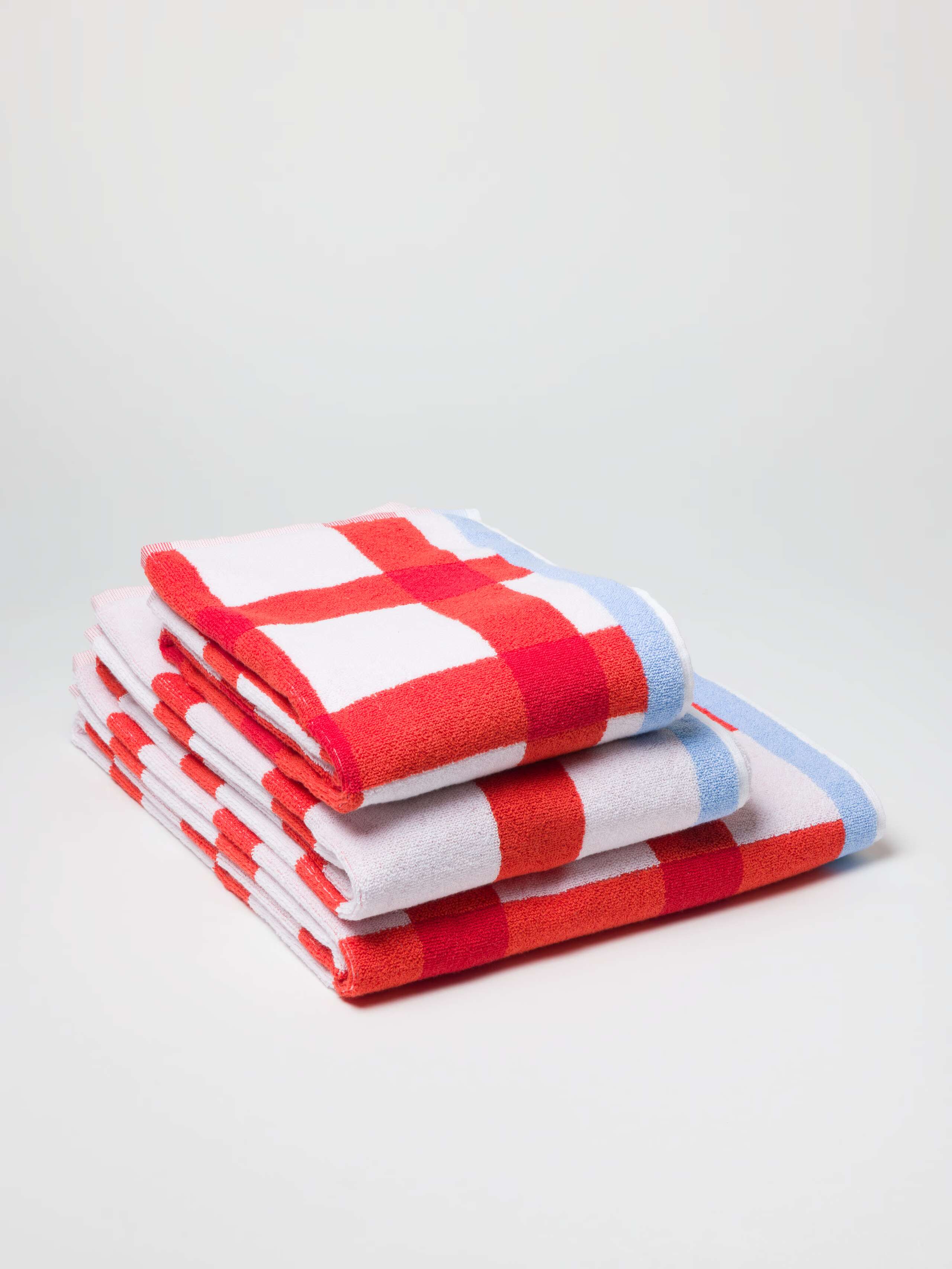 Terry bath towel in red vichy check with light blue borders in a stack