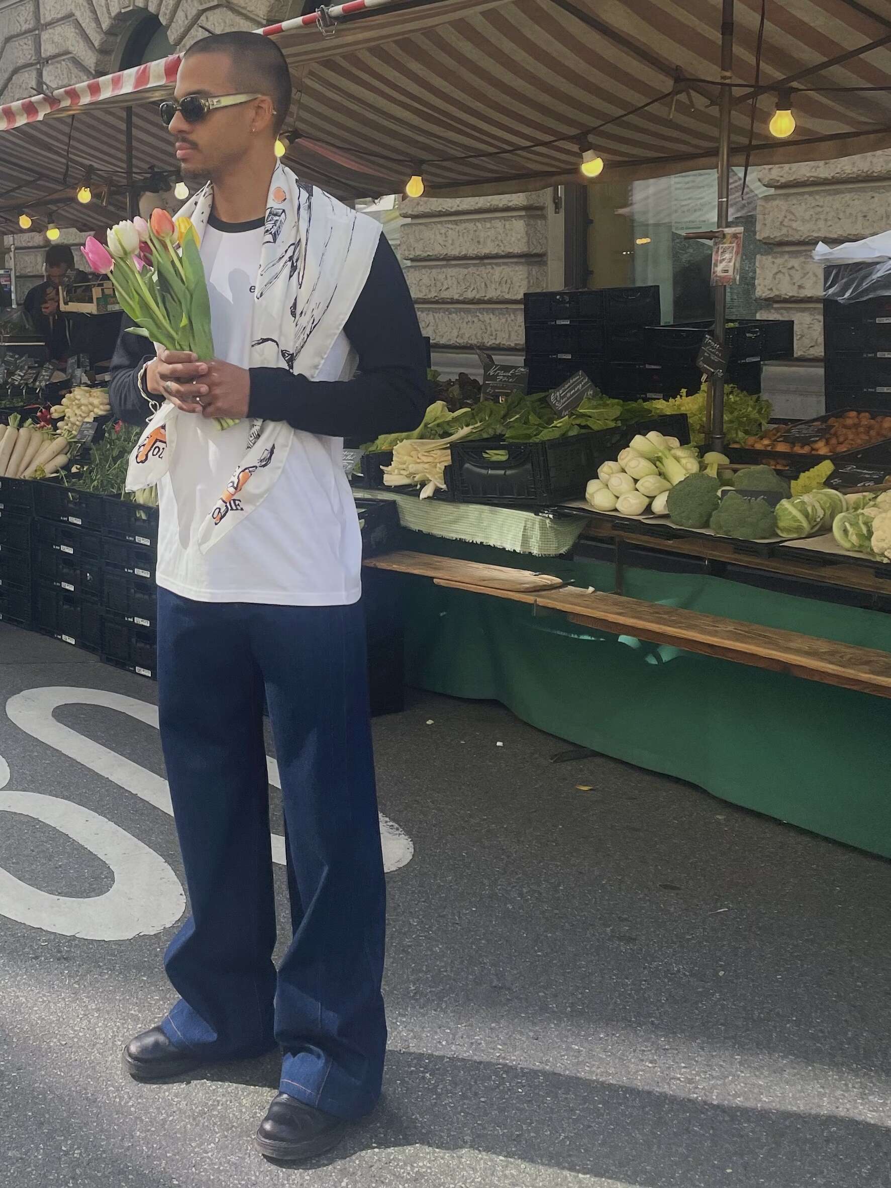 Picture of a young man holding flowers in front of a market stall