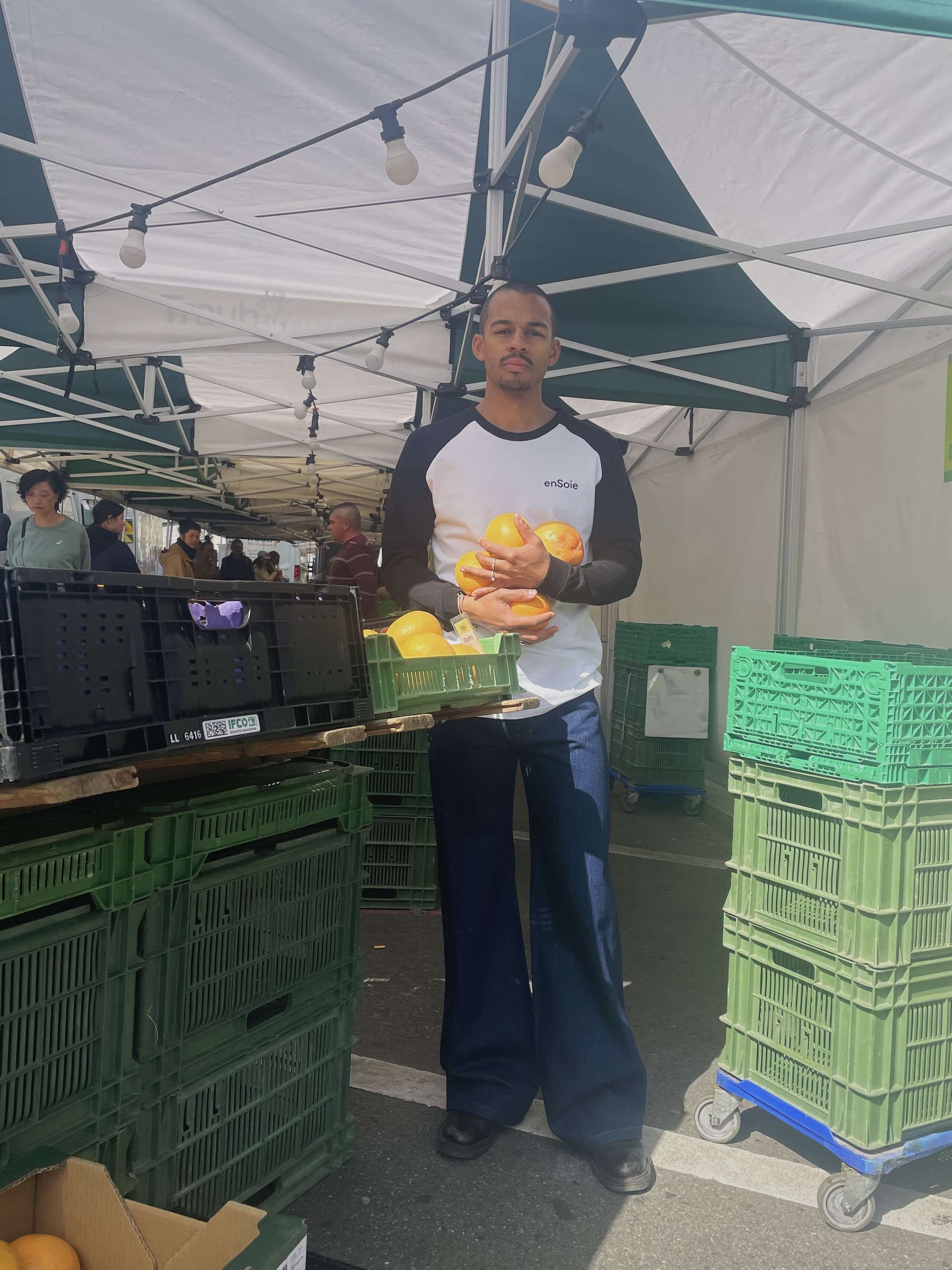 Picture of a young man holding oranges in front of a market stall