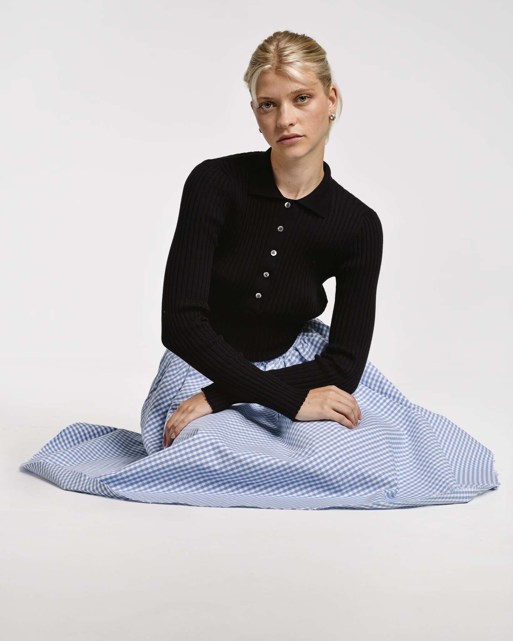 Model wearing the berta medium skirt in cerulean light blue vichy check cotton and venetia polo neck