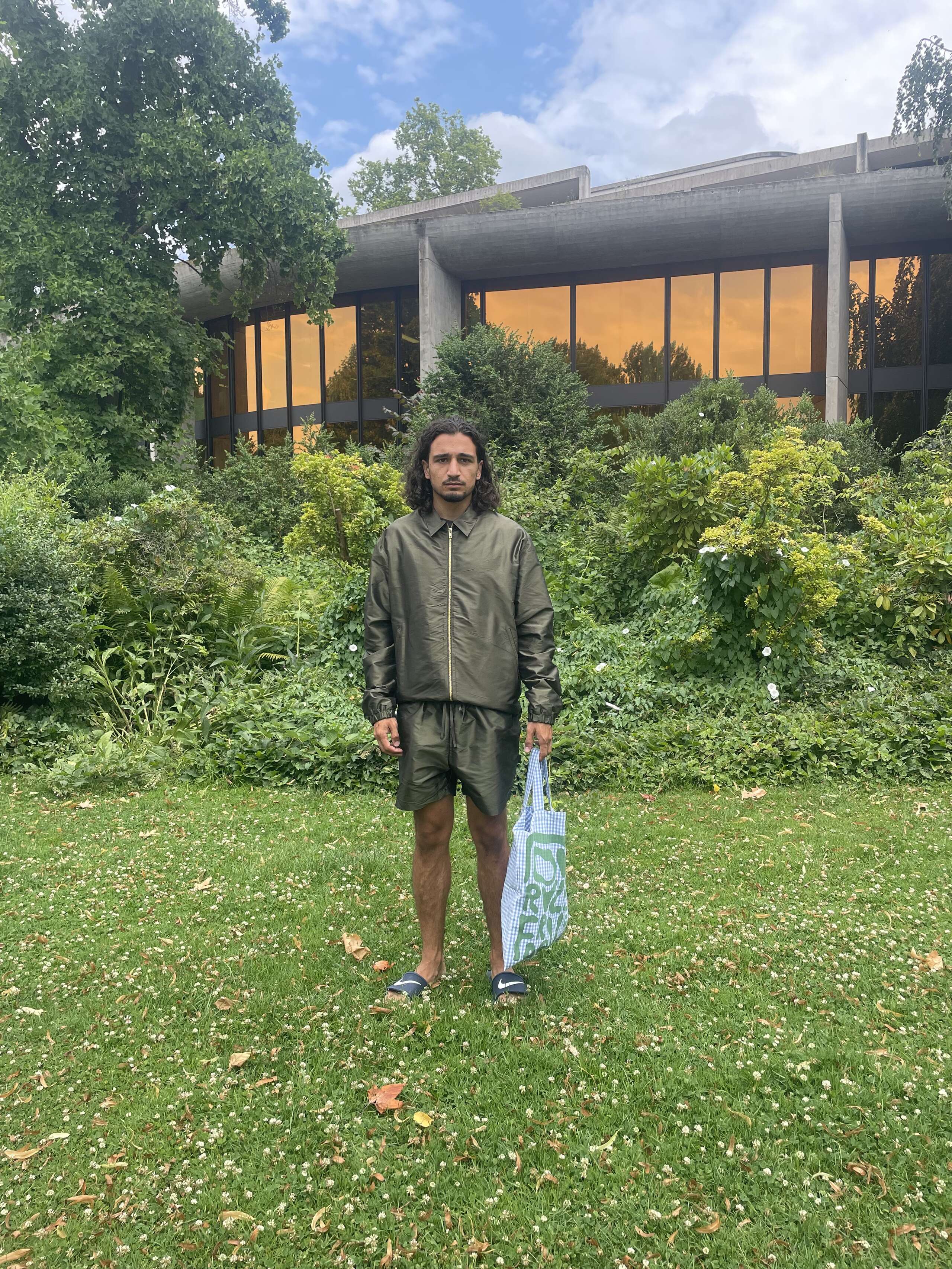 Male model wearing shorts and jacket holding a carry all bag