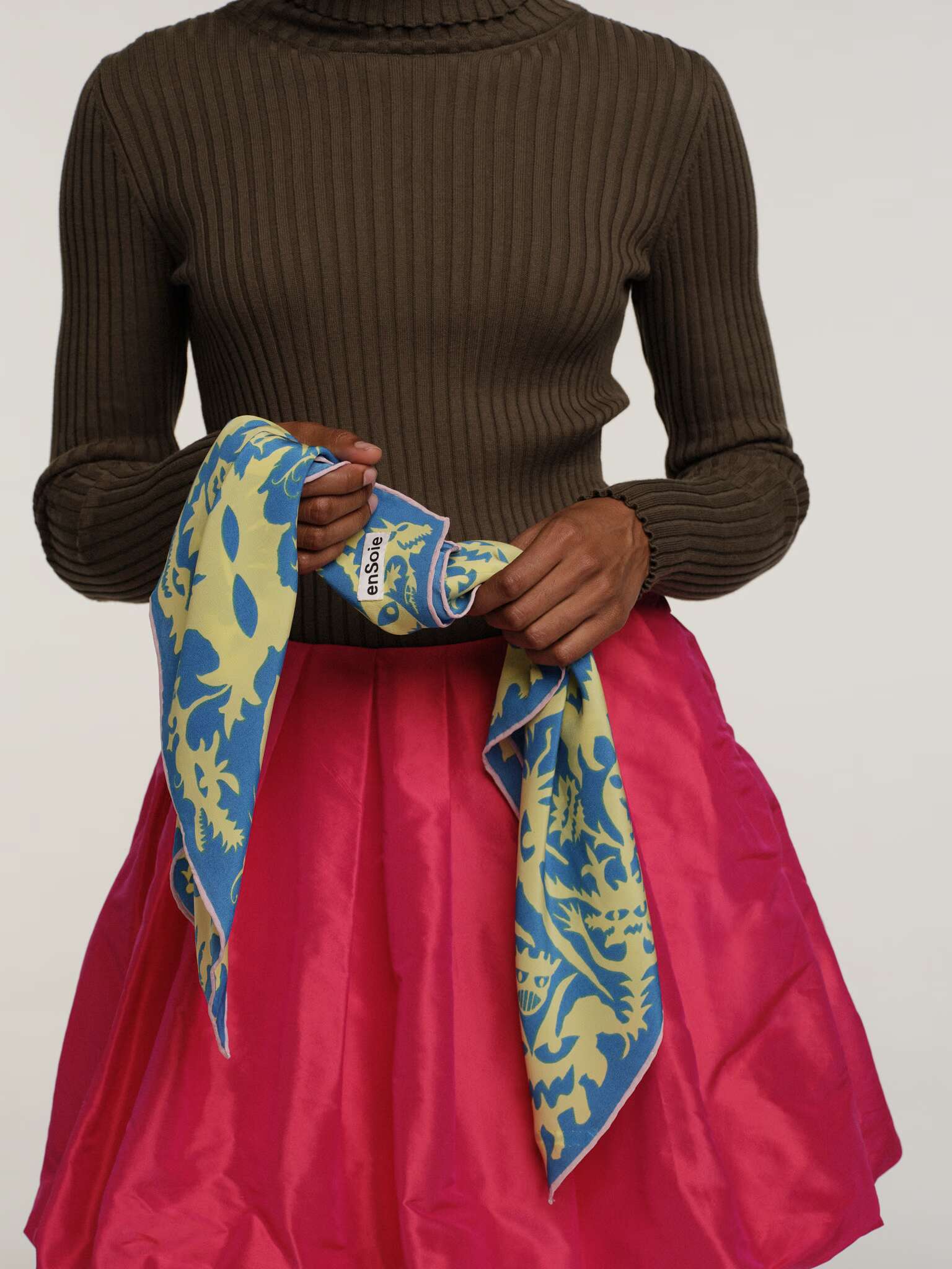 Picture of a women wearing a pink silk skirt and a khaki green turtleneck