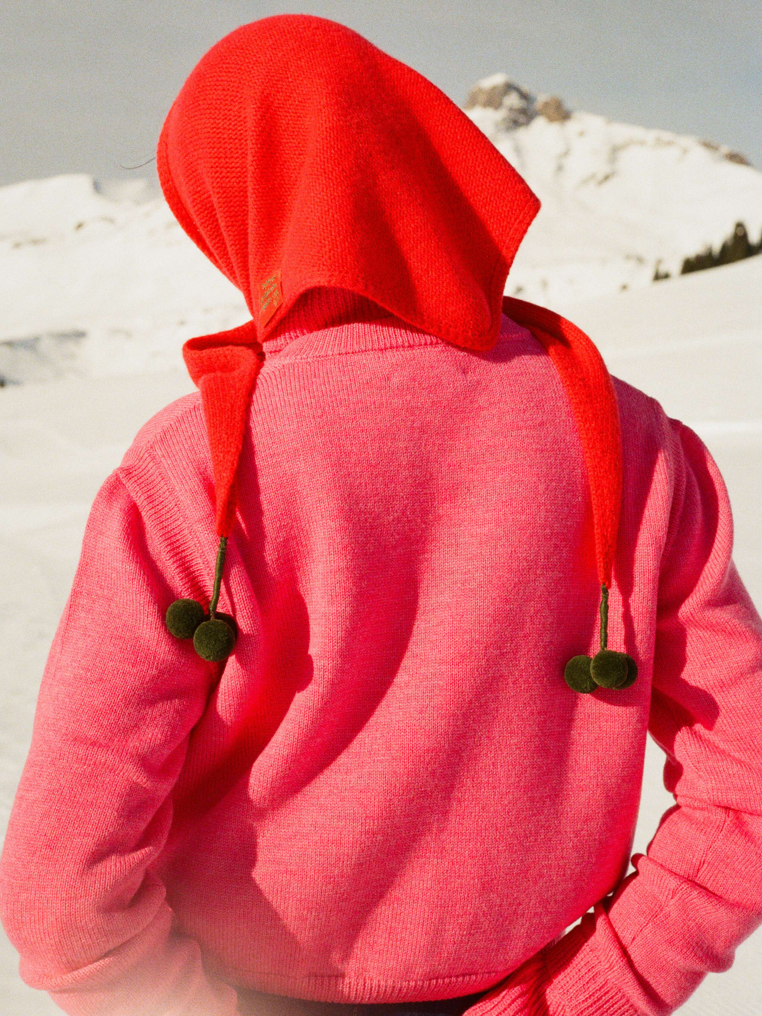 Picture of a women wearing a red knitted cashmere scarf around her head