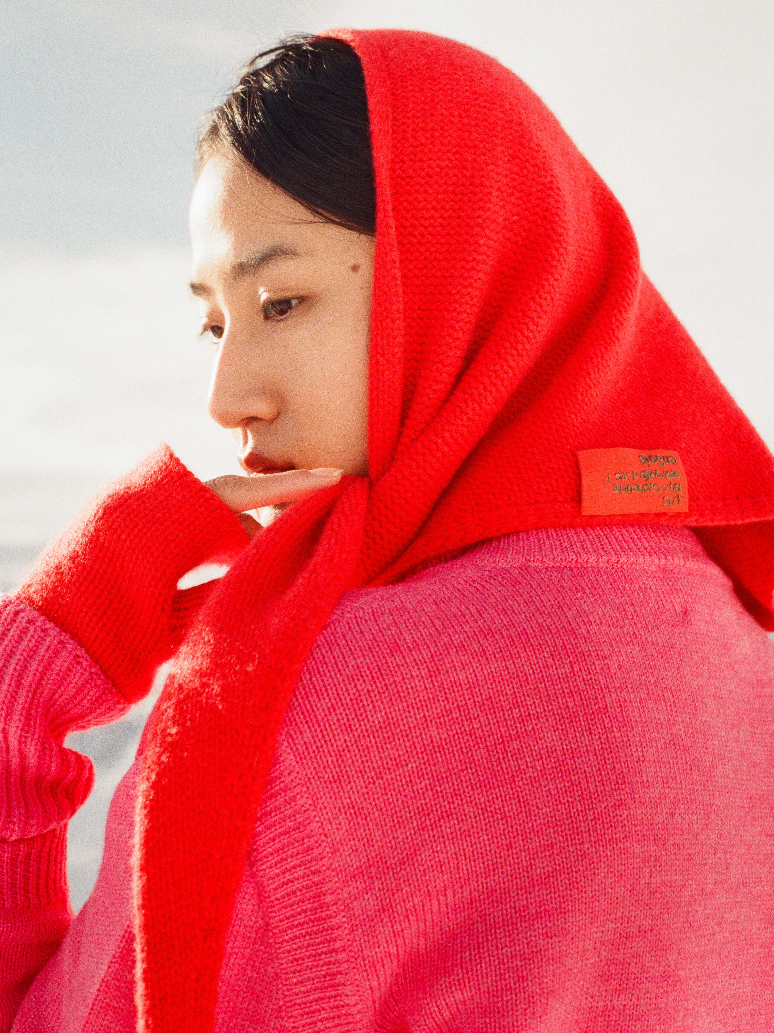 Picture of a women wearing a red knitted cashmere scarf around her head