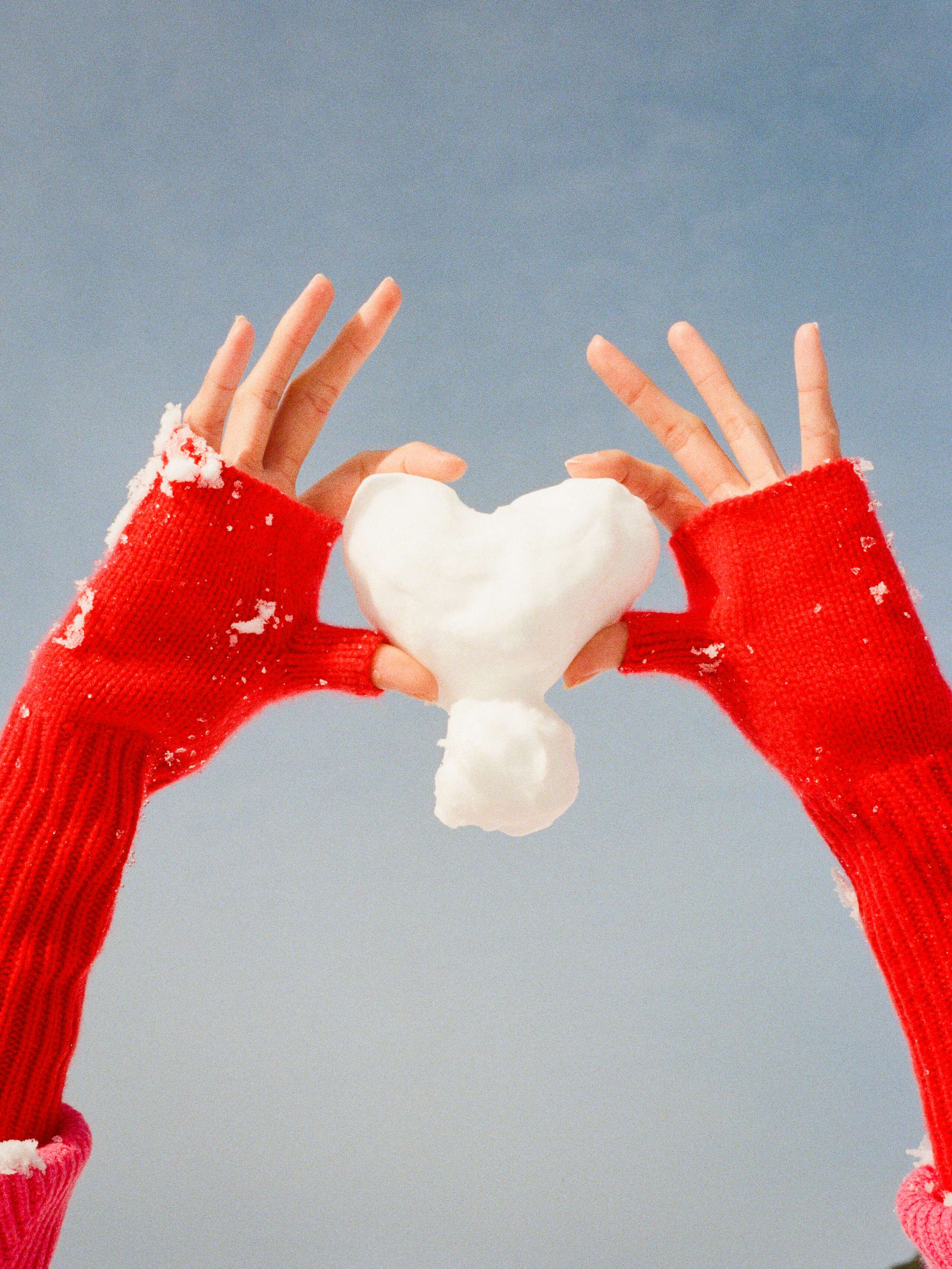 Two hand holding a heart made of snow