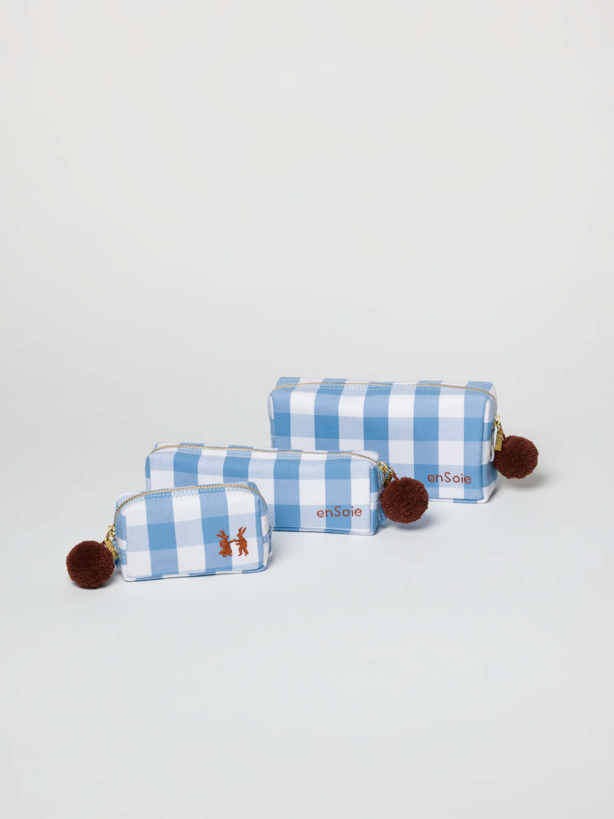 toiletry cases in three sizes in vichy check calm blue light blue with brown pompon