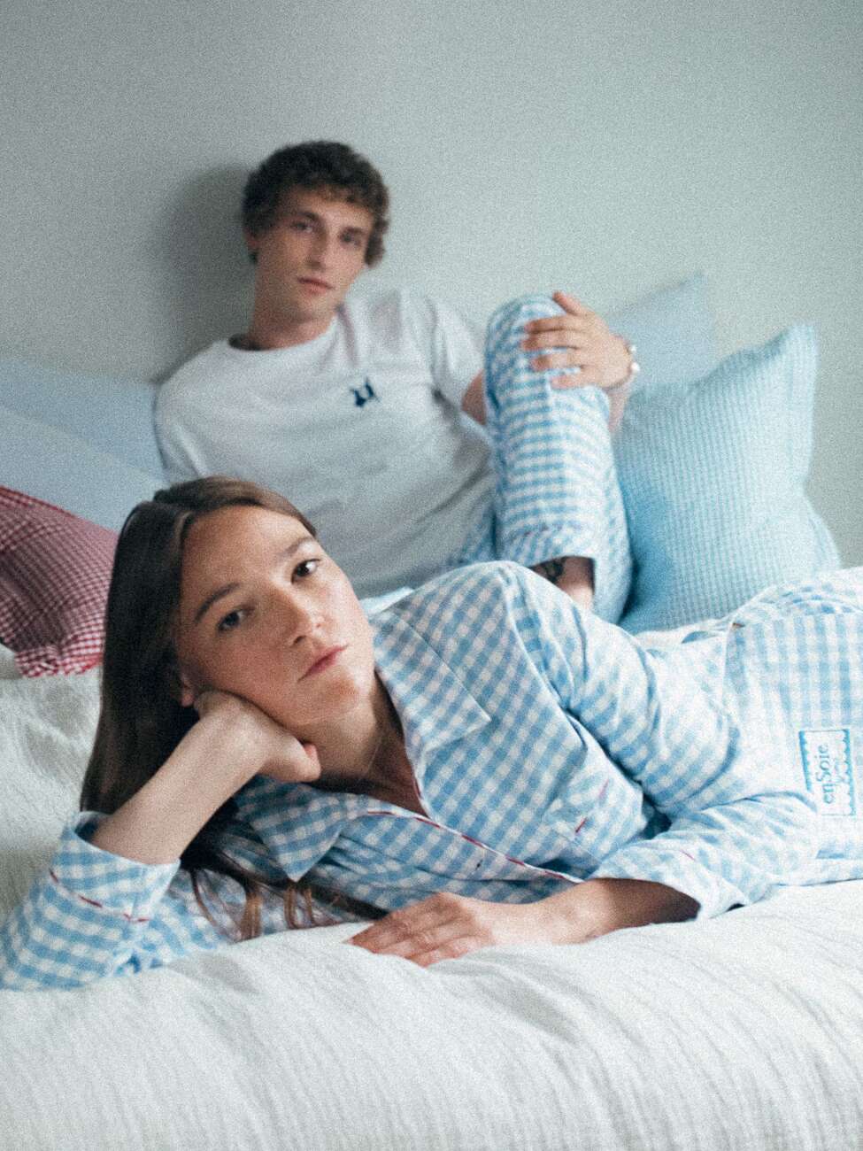 Picture of a couple sitting on a bed wearing light blue pyjamas