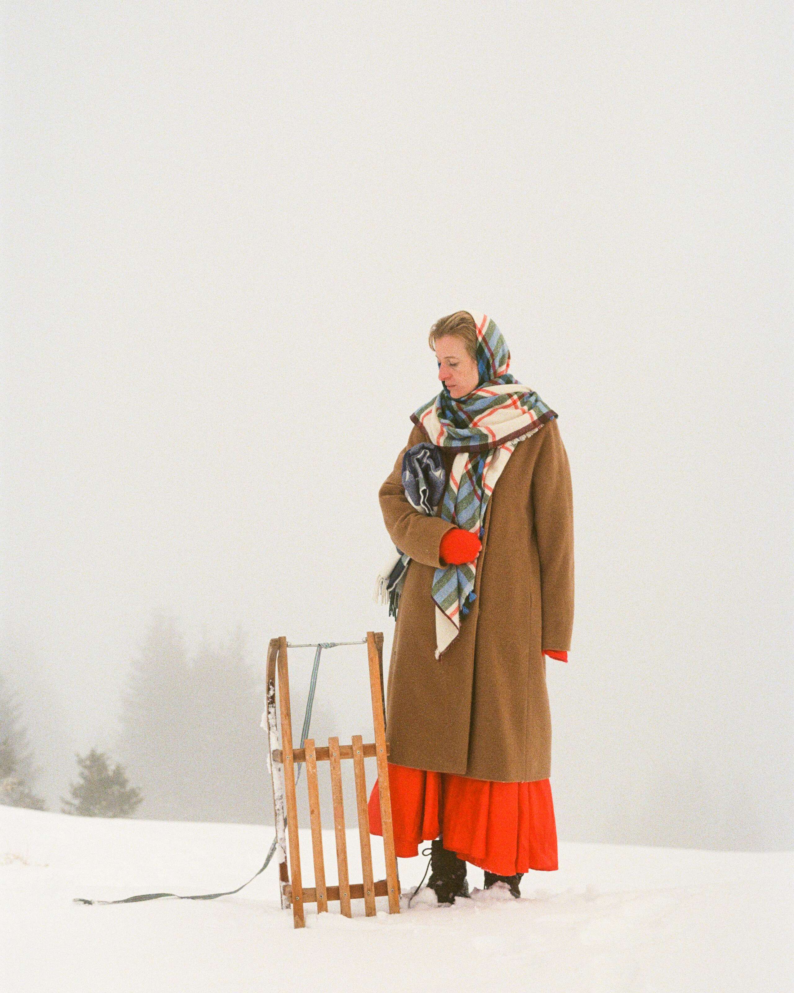 A women standing next to a sledge in a snowy winter landscape